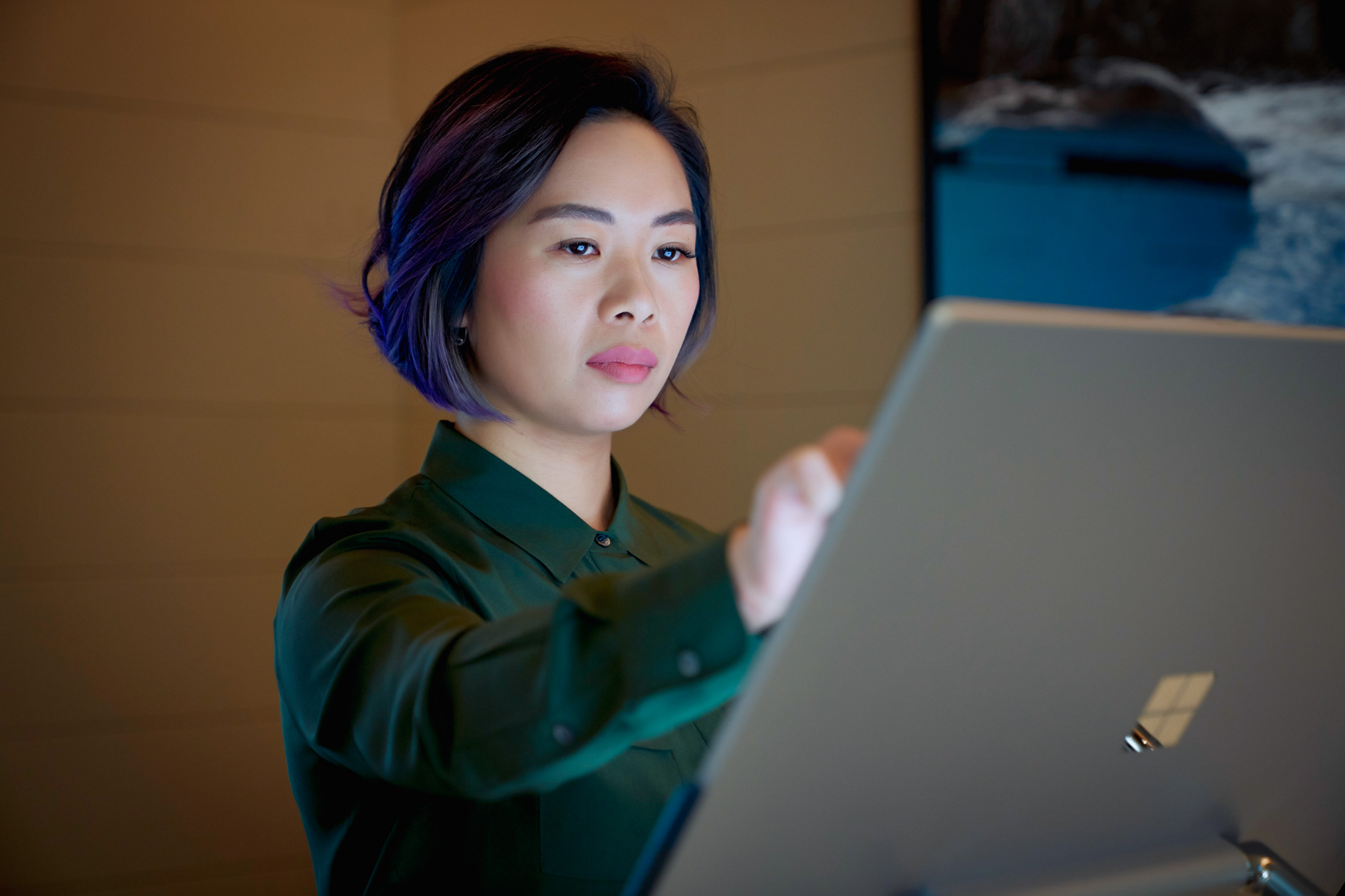 Asian woman with purpler hair working on touch screen computer