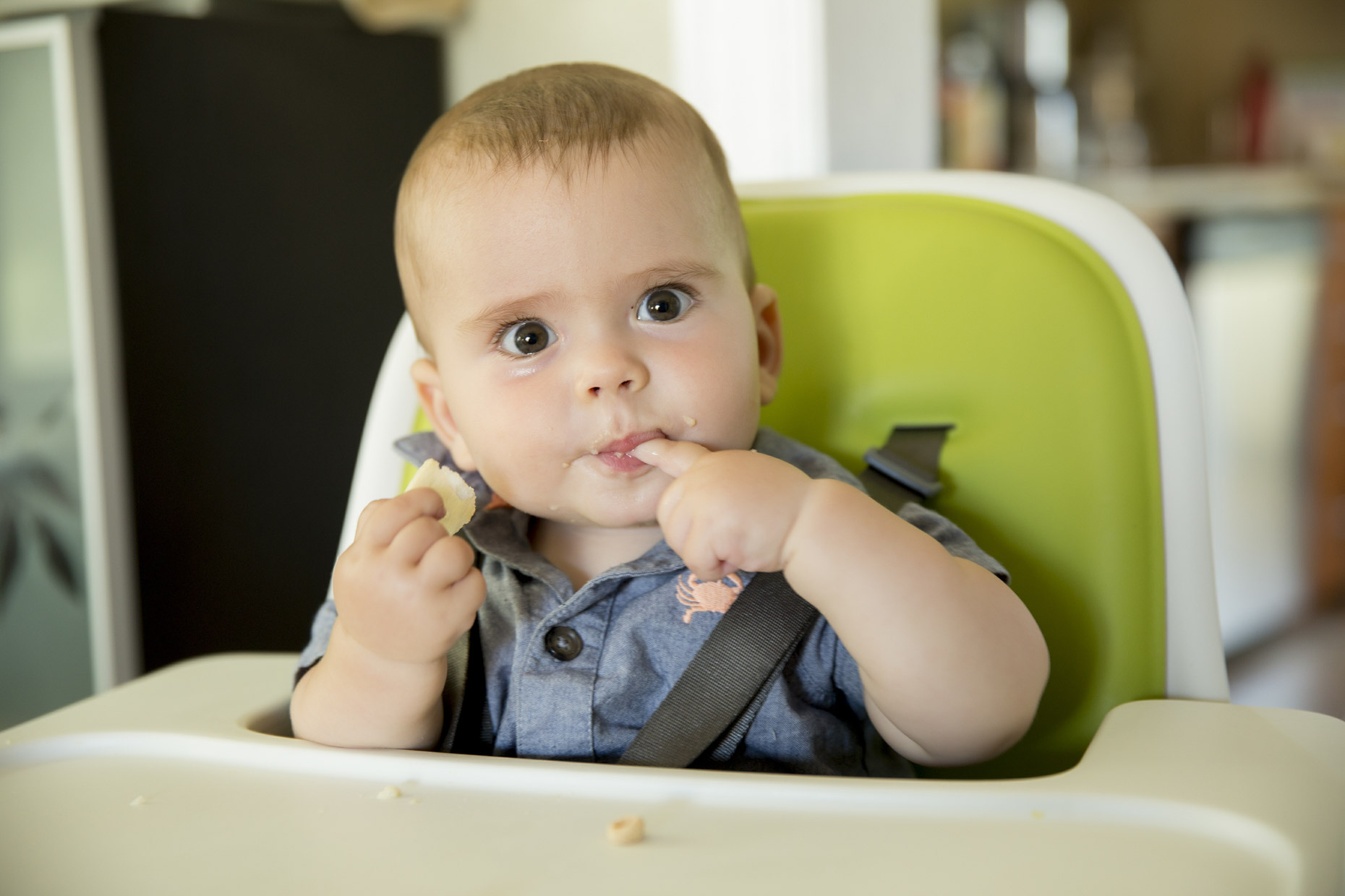 Baby sitting in high chair with finger in mouth