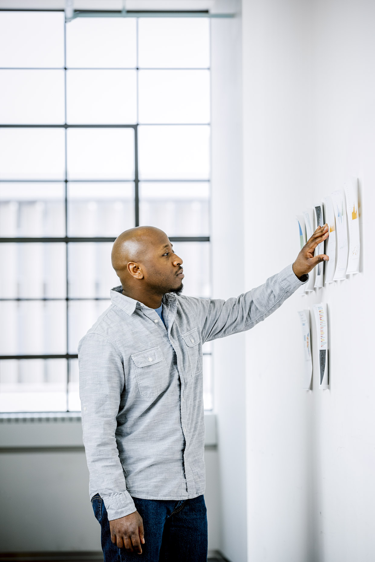 Black black business man looking at charts on wall in office