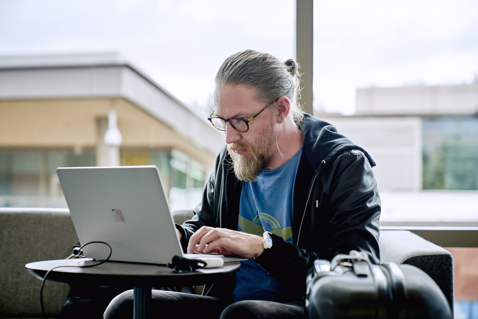 Bearded man working on laptop in airport
