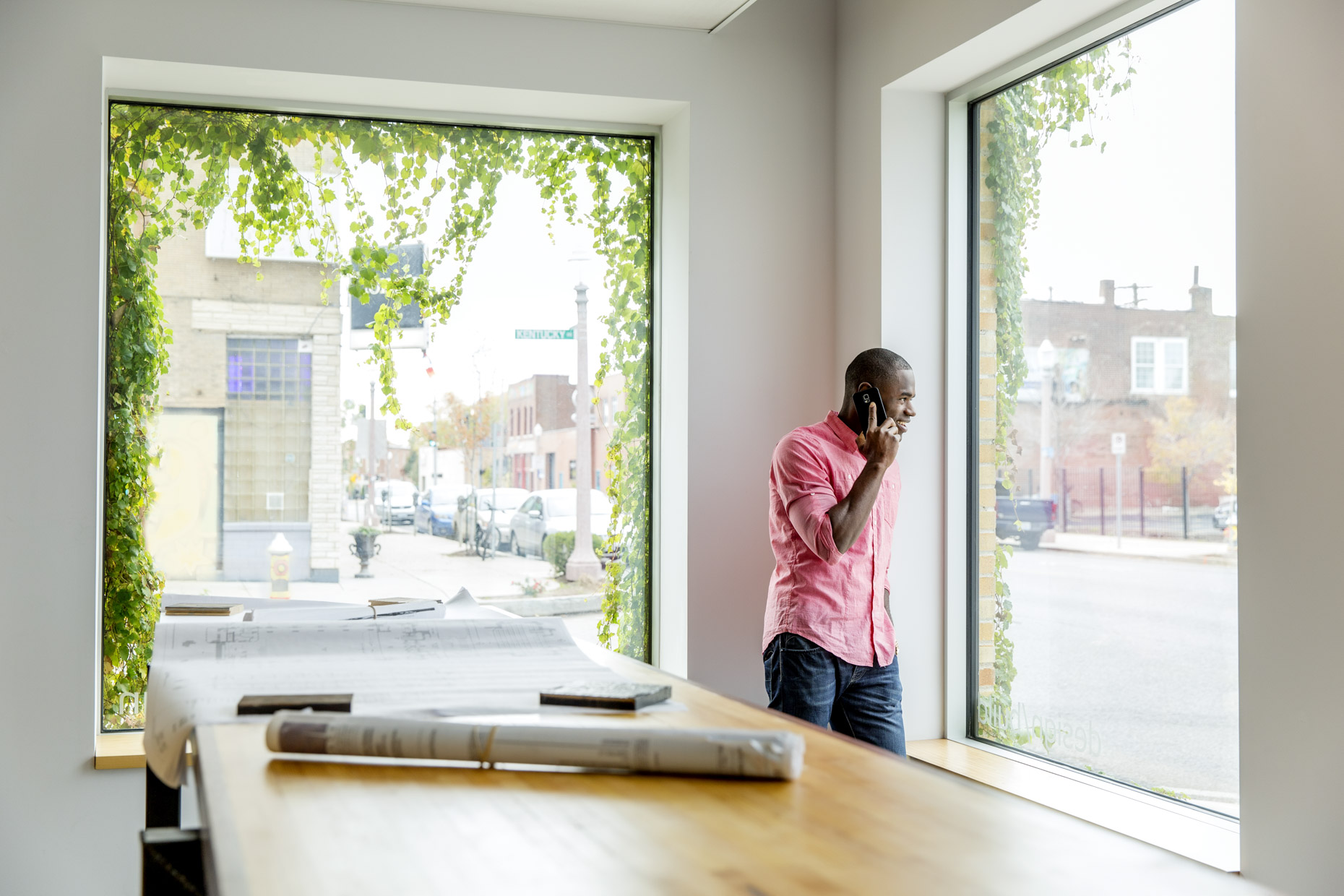 Black architect talking on the phone looking out window