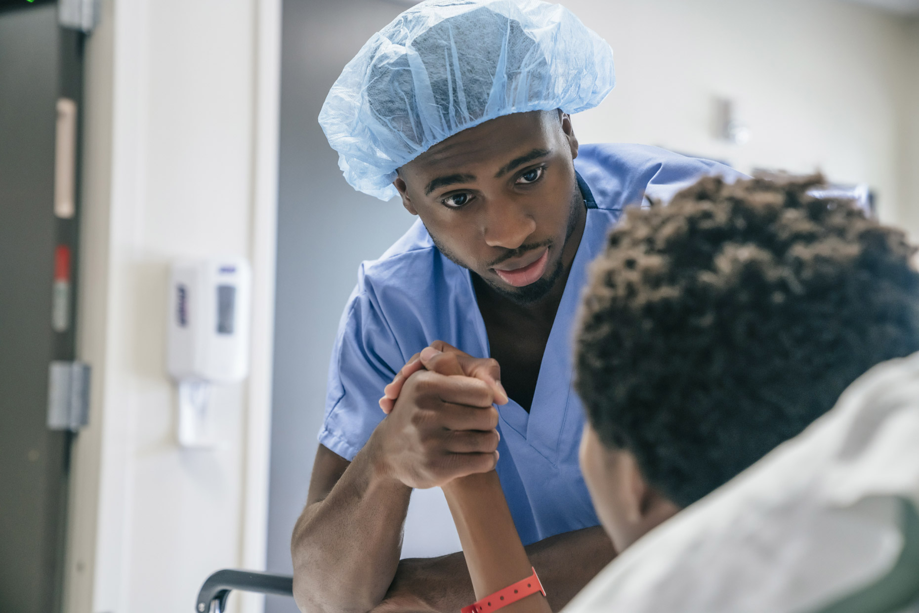 Black male nurse clasping teen boy
