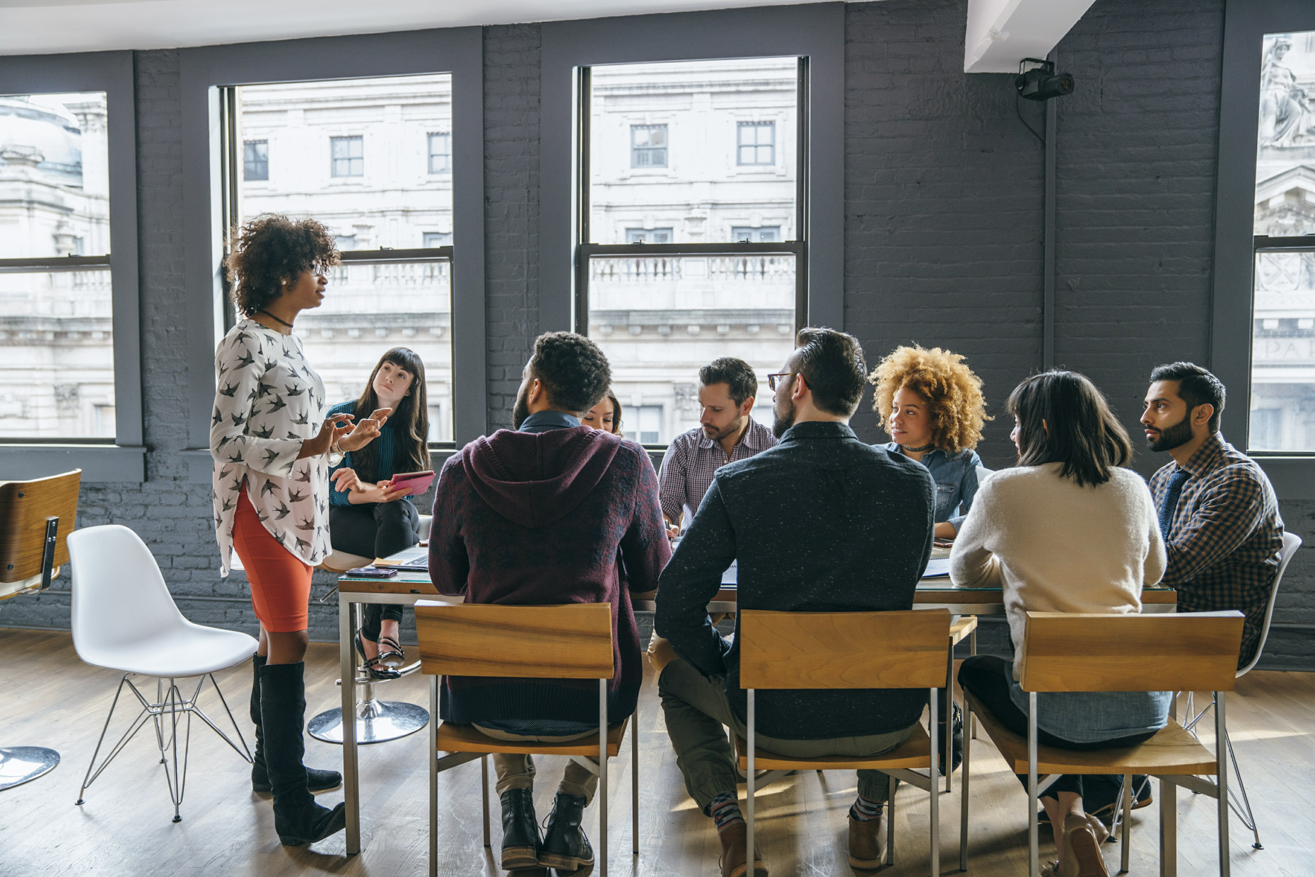Black woman leading tech office meeting around conference table
