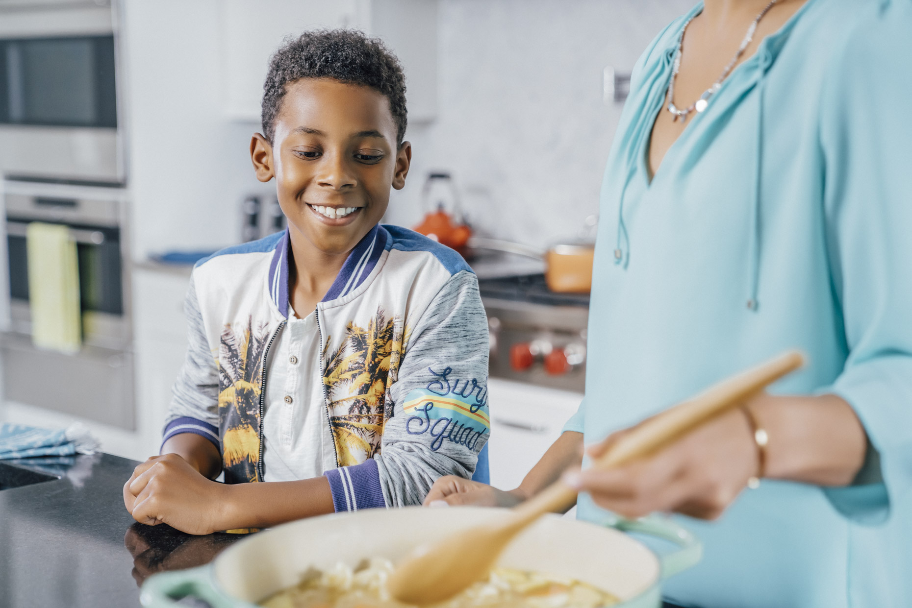 Boy looking excitedly at pot of food mom is making