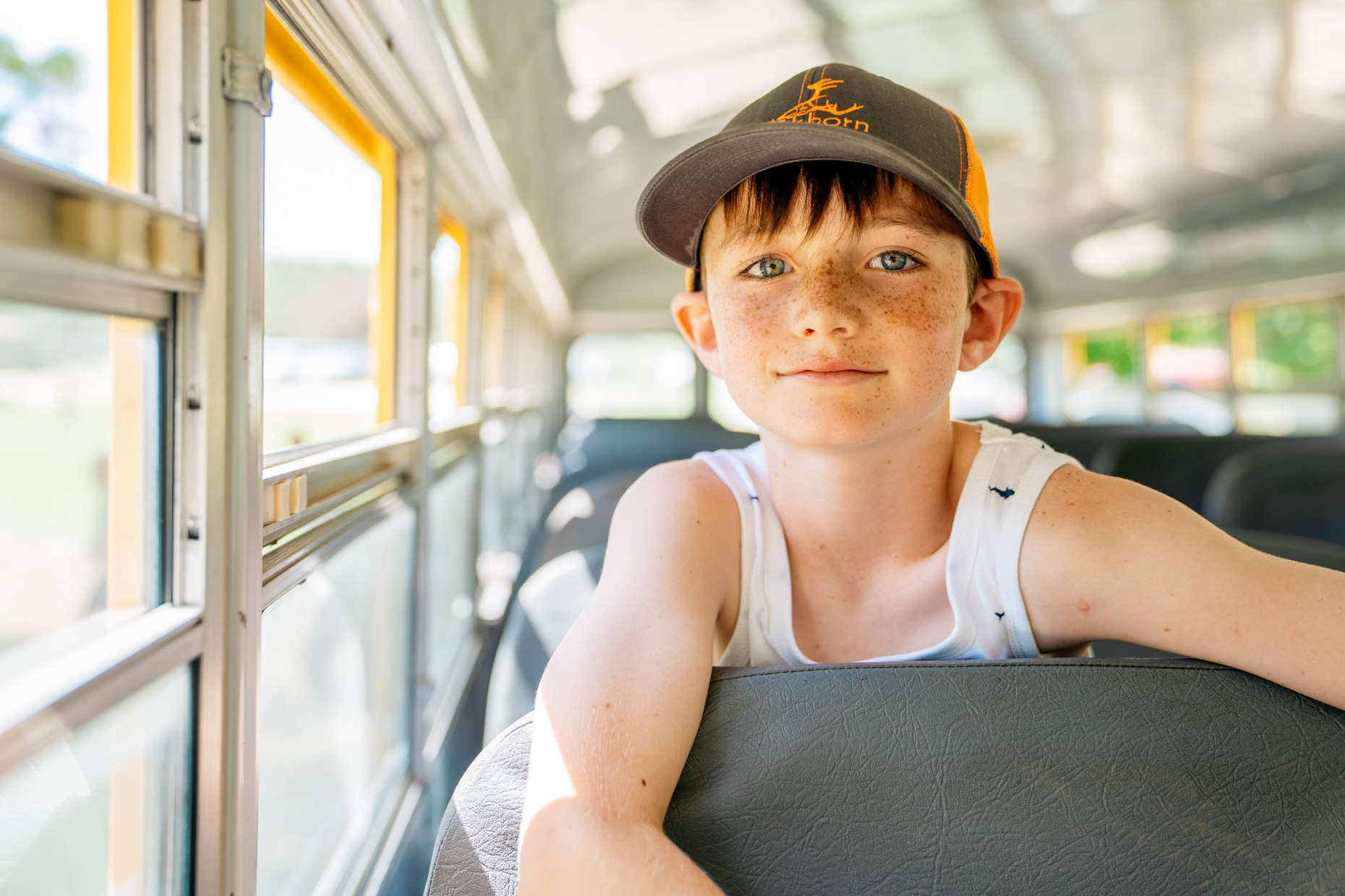Boy-smiling-wearing-hat-on-bus-is20210716_Deer_Creek_0865