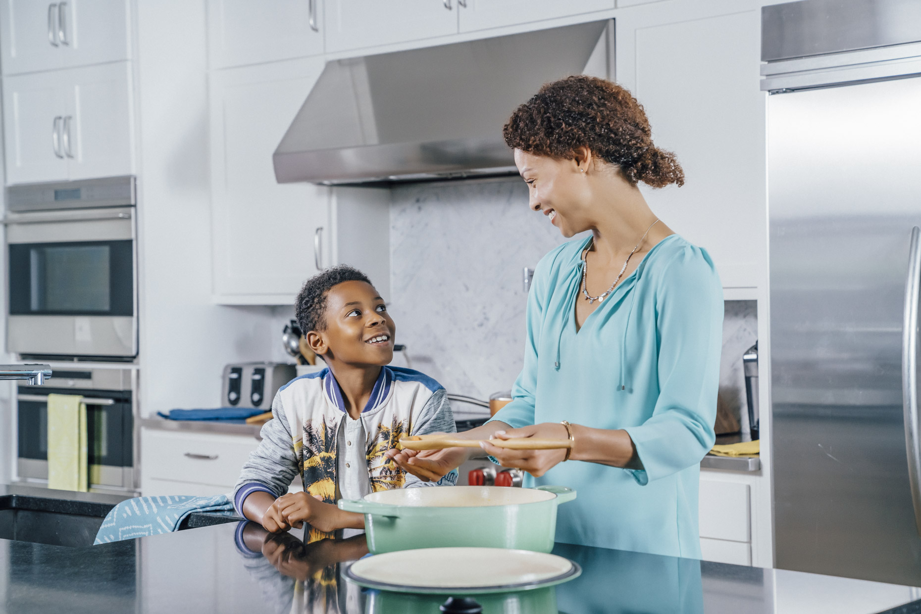 Boy talking with mom cooking in kitchen