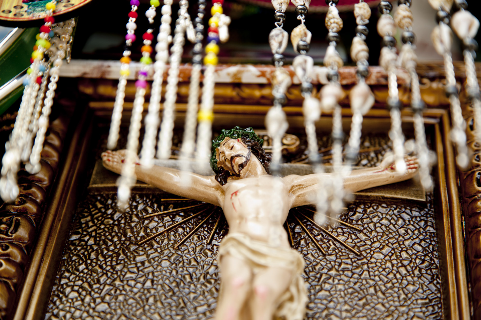 Close-up of Jesus sculpture behind strings of beads
