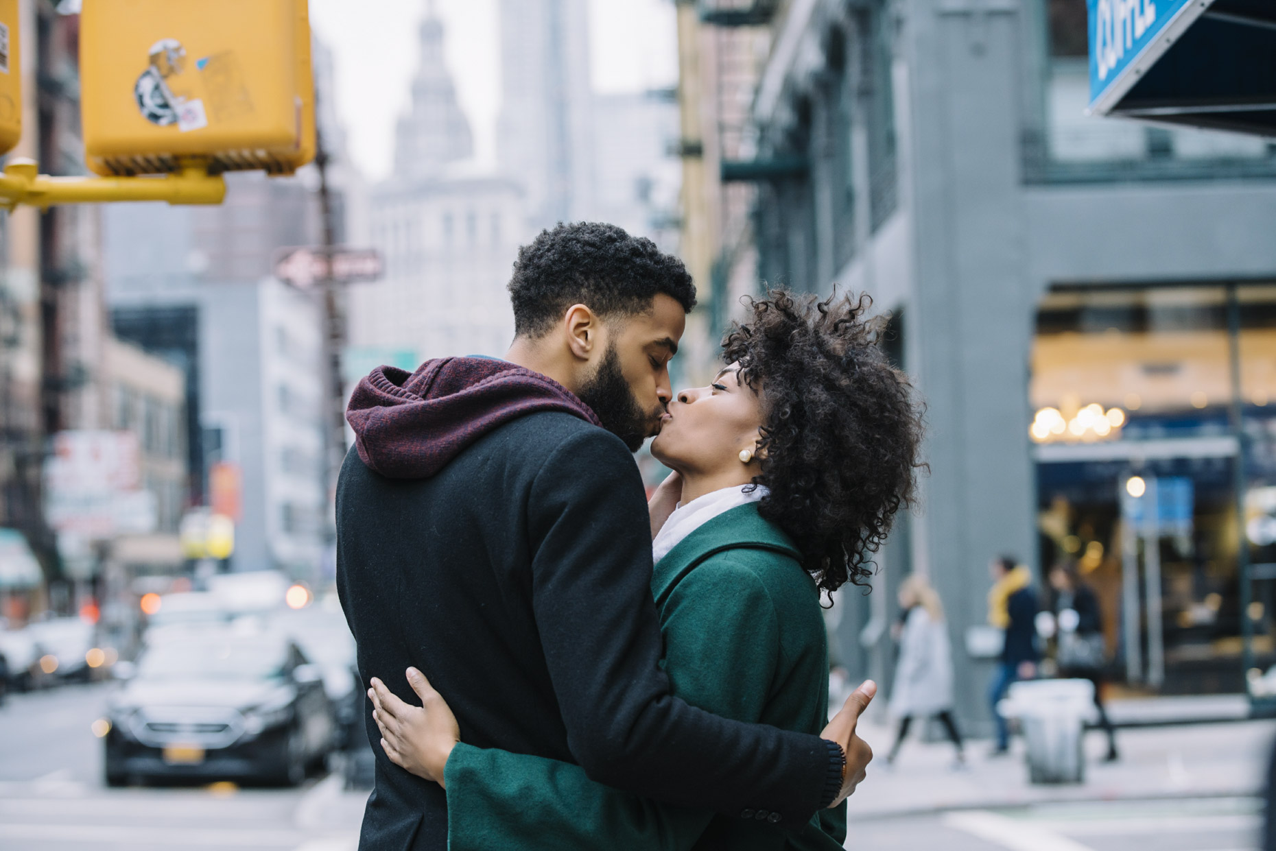 Couple in coats kissing at cross walk in NYC