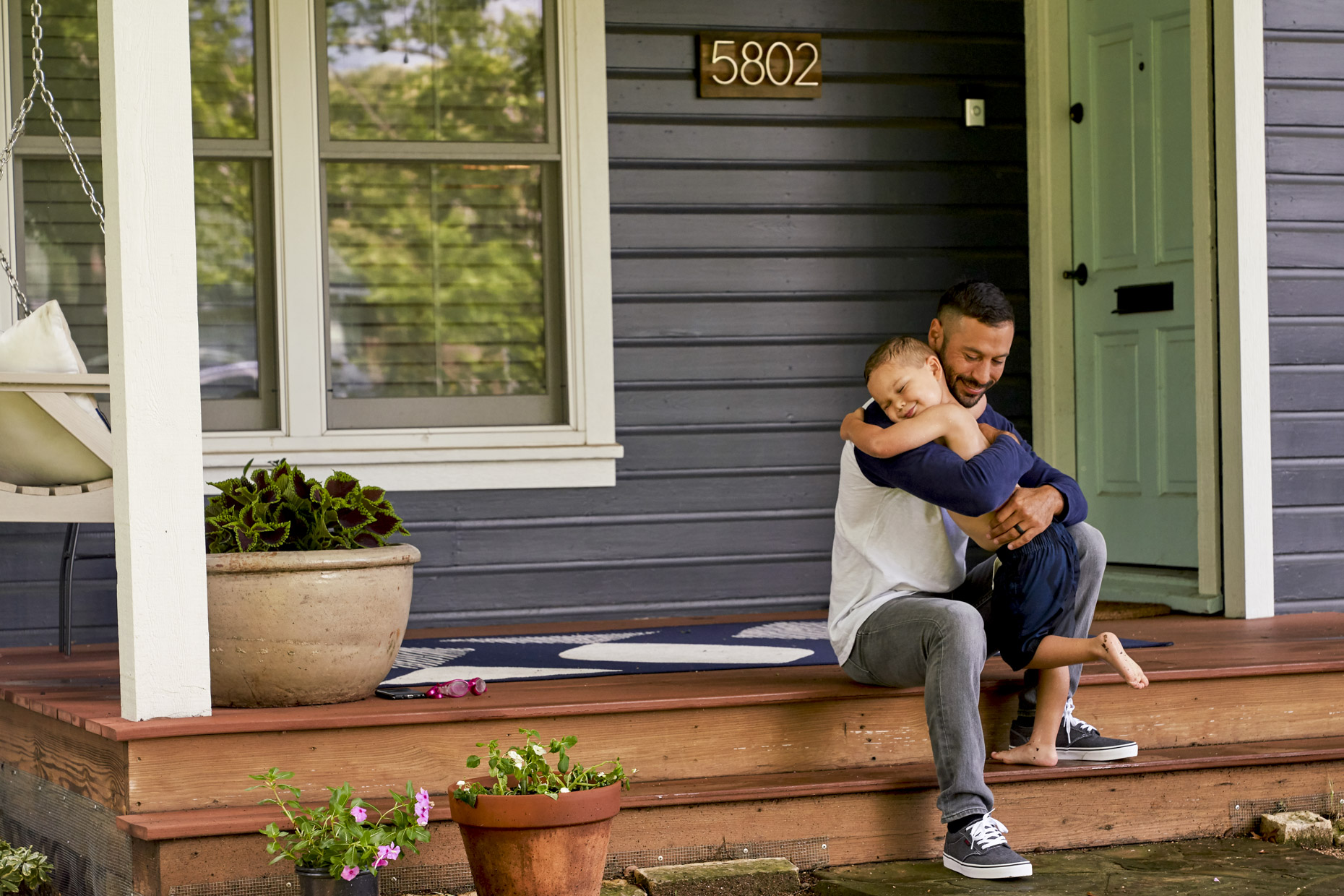 Dad hugging son on front porch