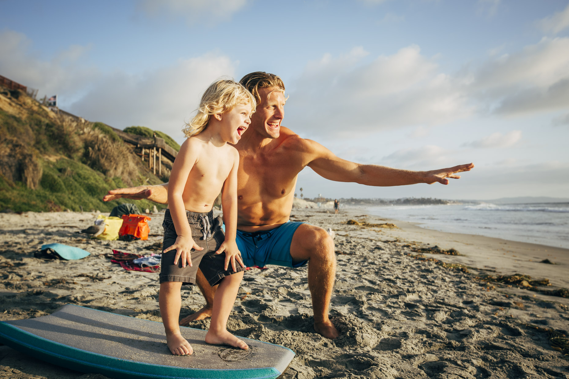 Dad teaching son how to surf on beach