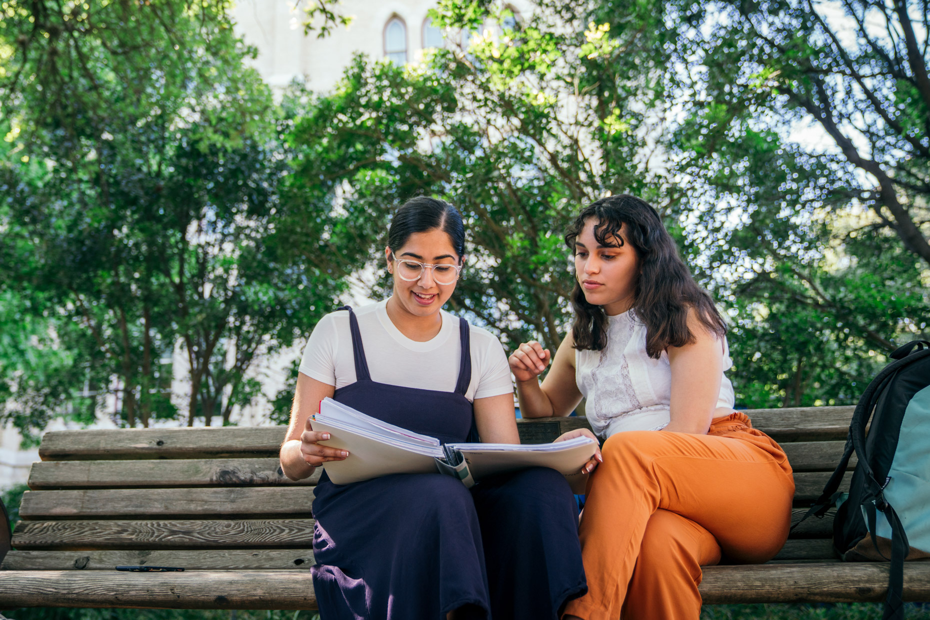Female college students studying outside on bench