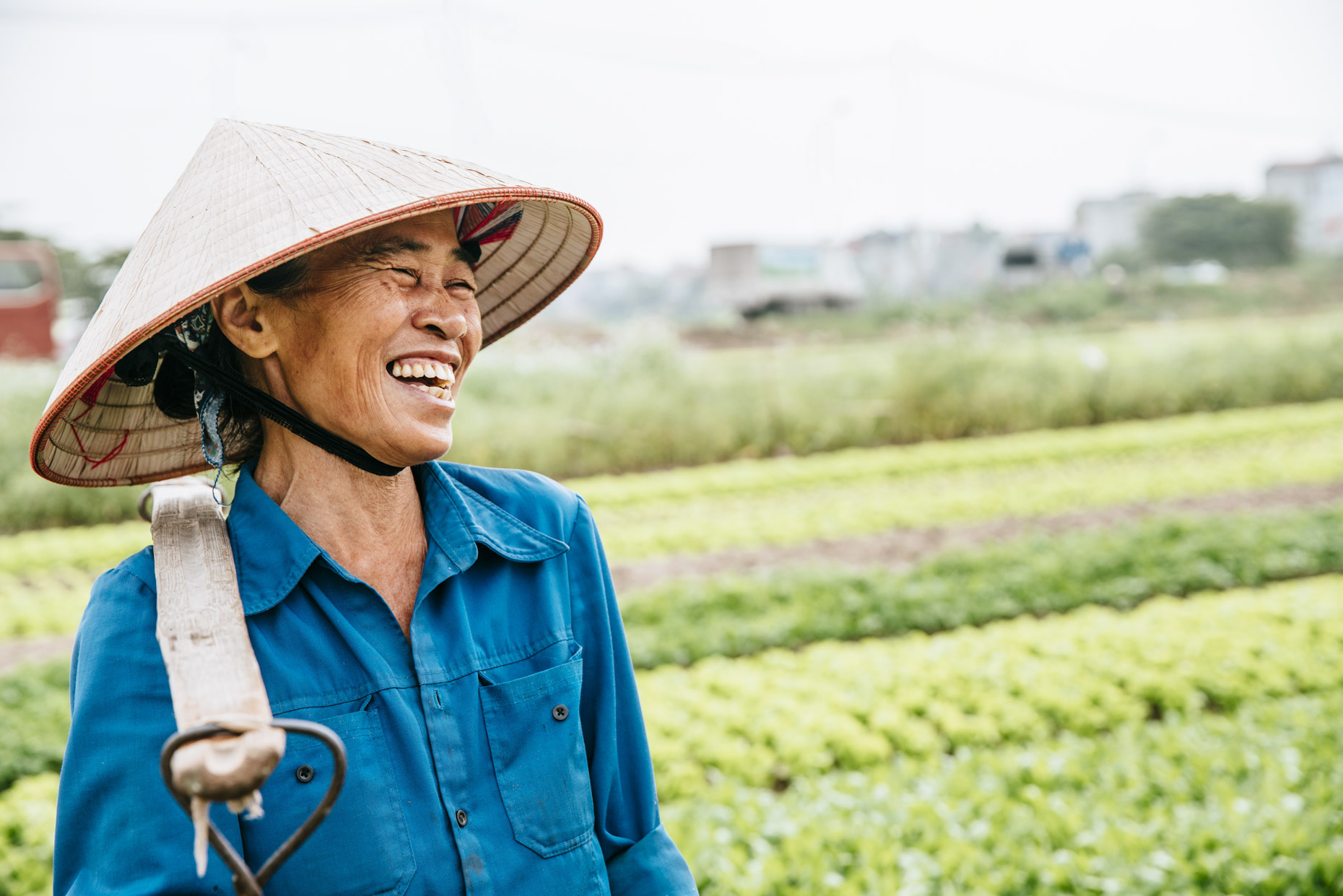 Female vietnamese farmer standing in field laughing 