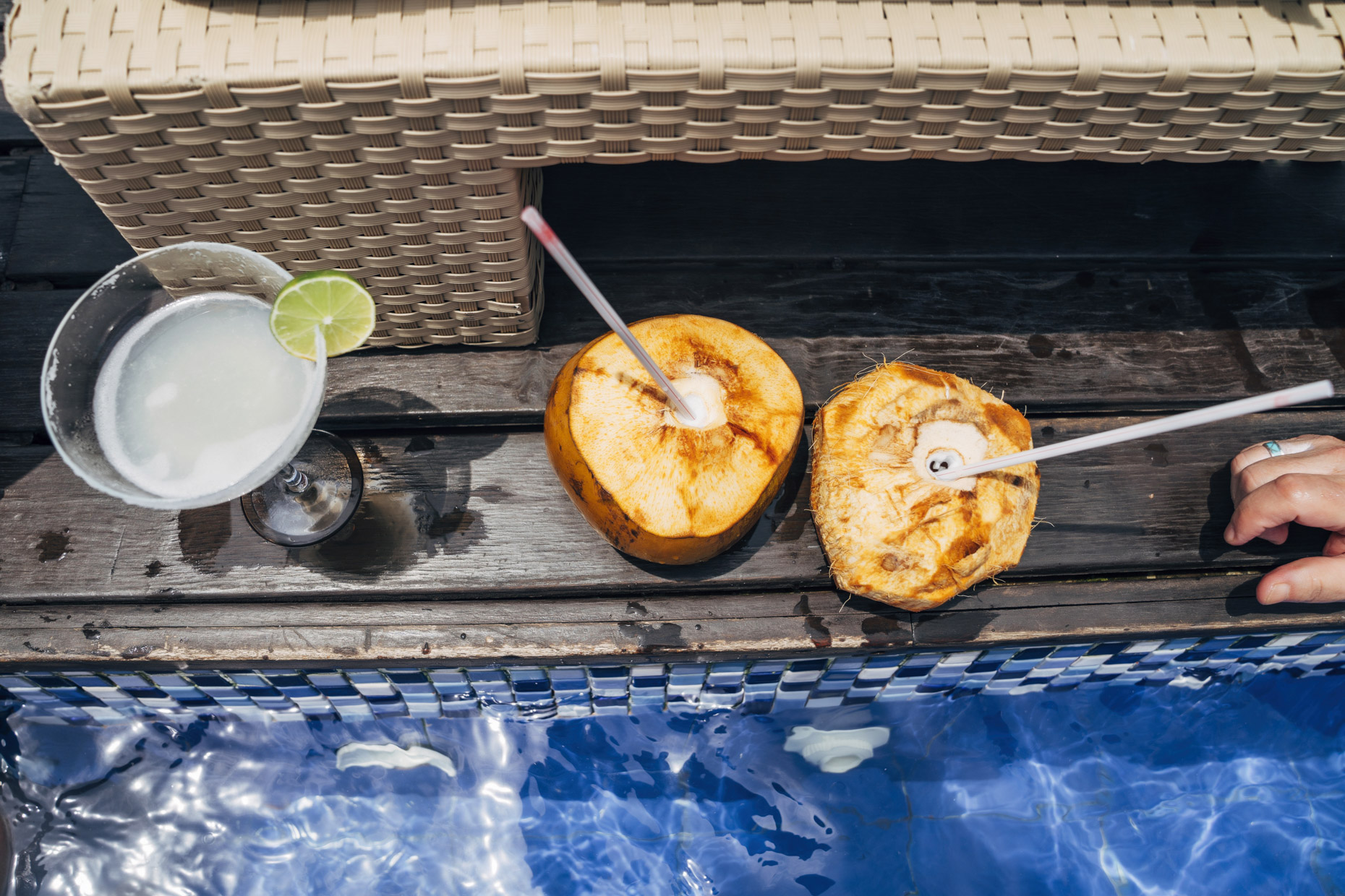 Fresh coconuts with straws and margarita cocktail poolside