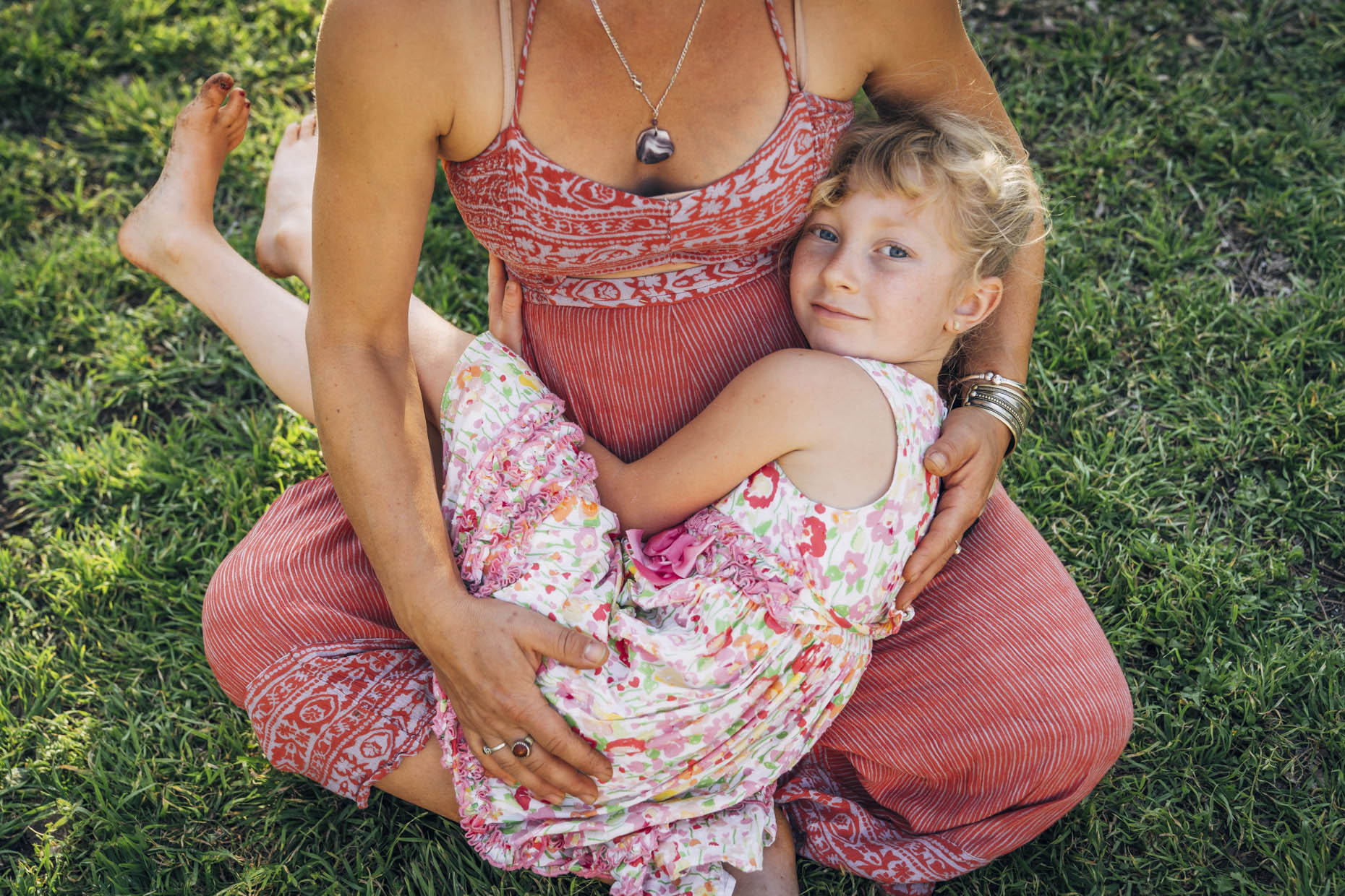 Girl in dress laying in pregnant mom lap hugging stomach