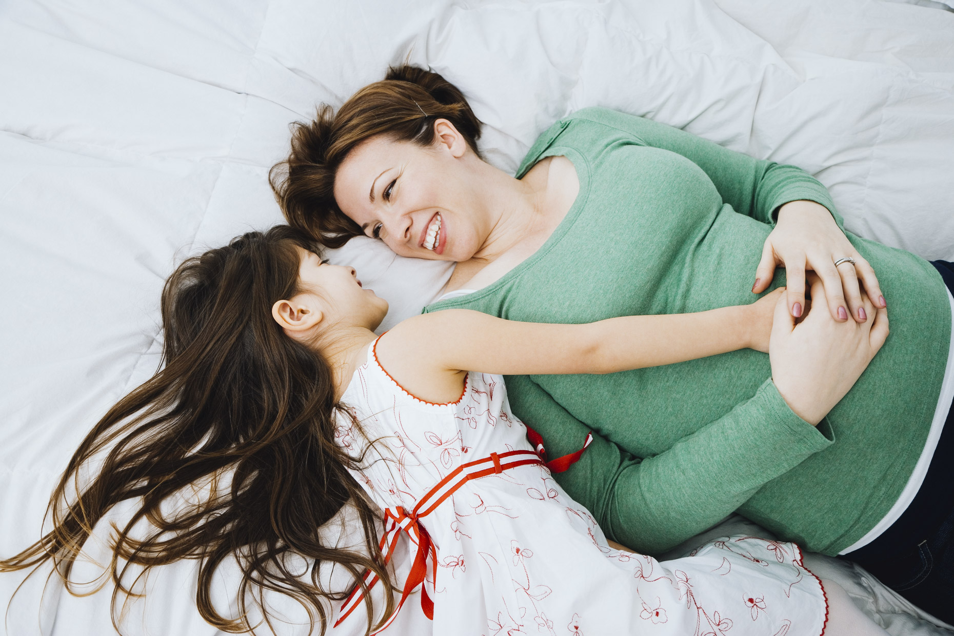 Girl-laying-on-bed-with-pregnant-mom-touching-belly-Inti-St-Clair-20071218168copy