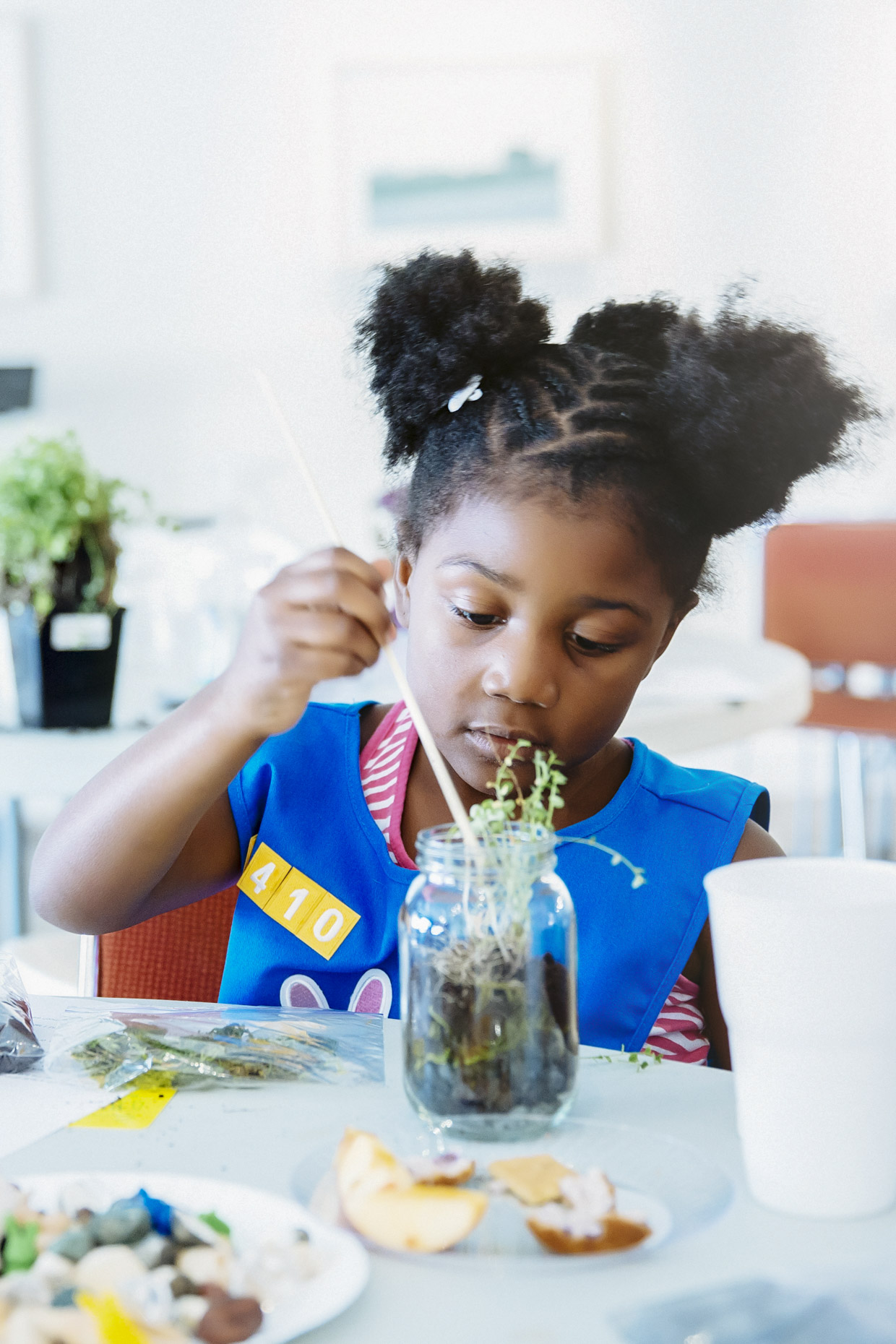 Girl scout with afro puffs planting in glass jar