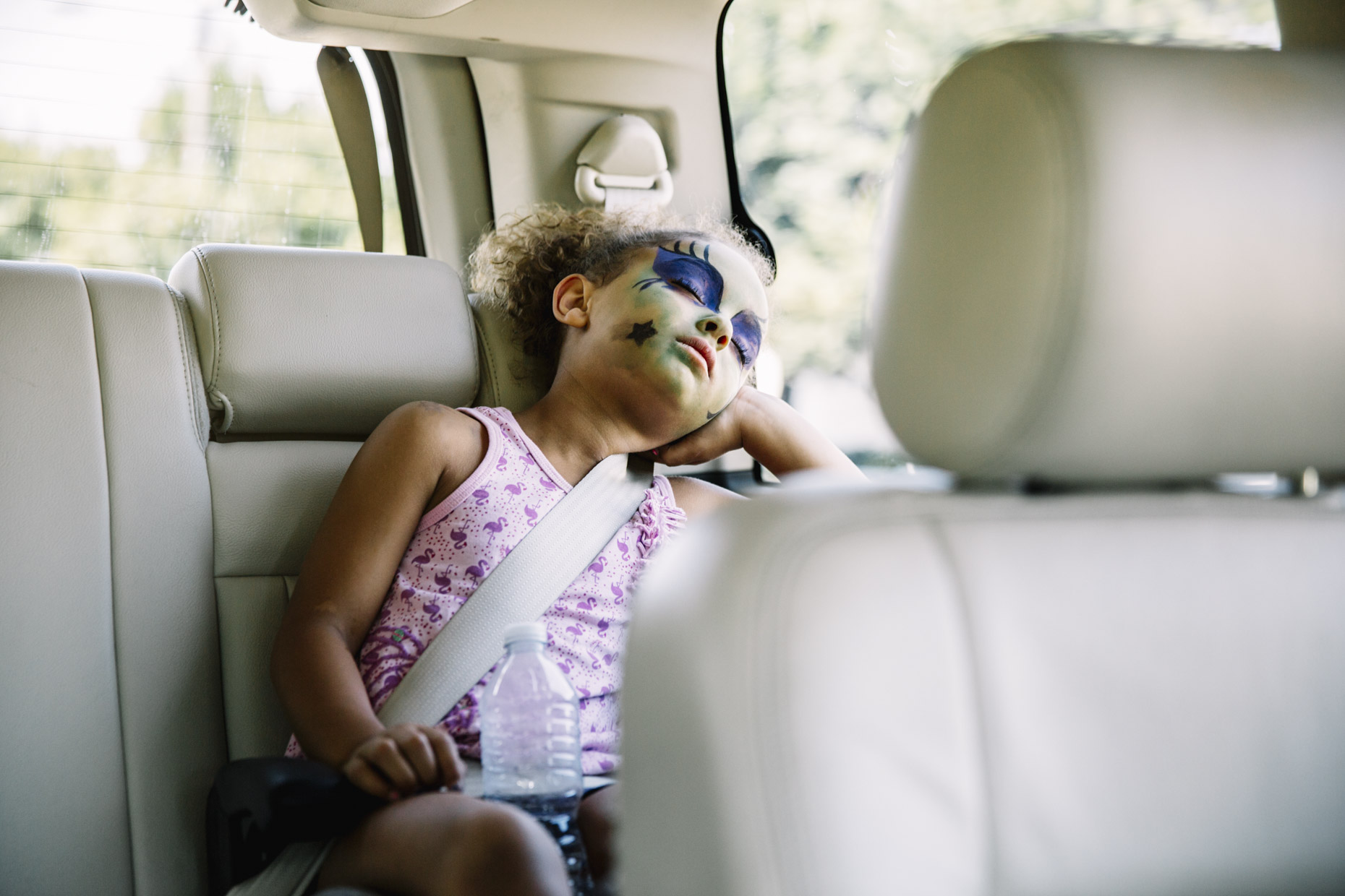 Girl with painted face sleeping in car seat