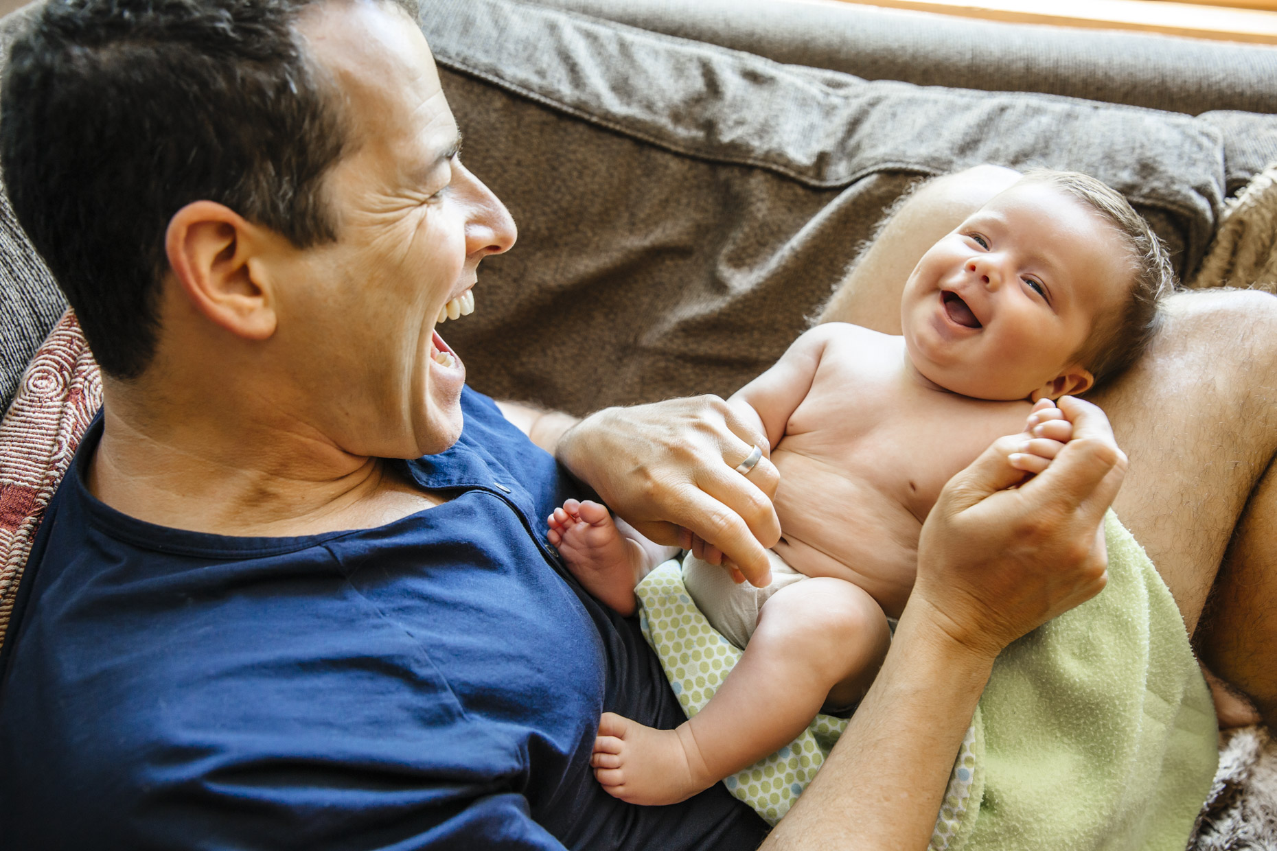 Happy dad playing with smiling baby on the couch