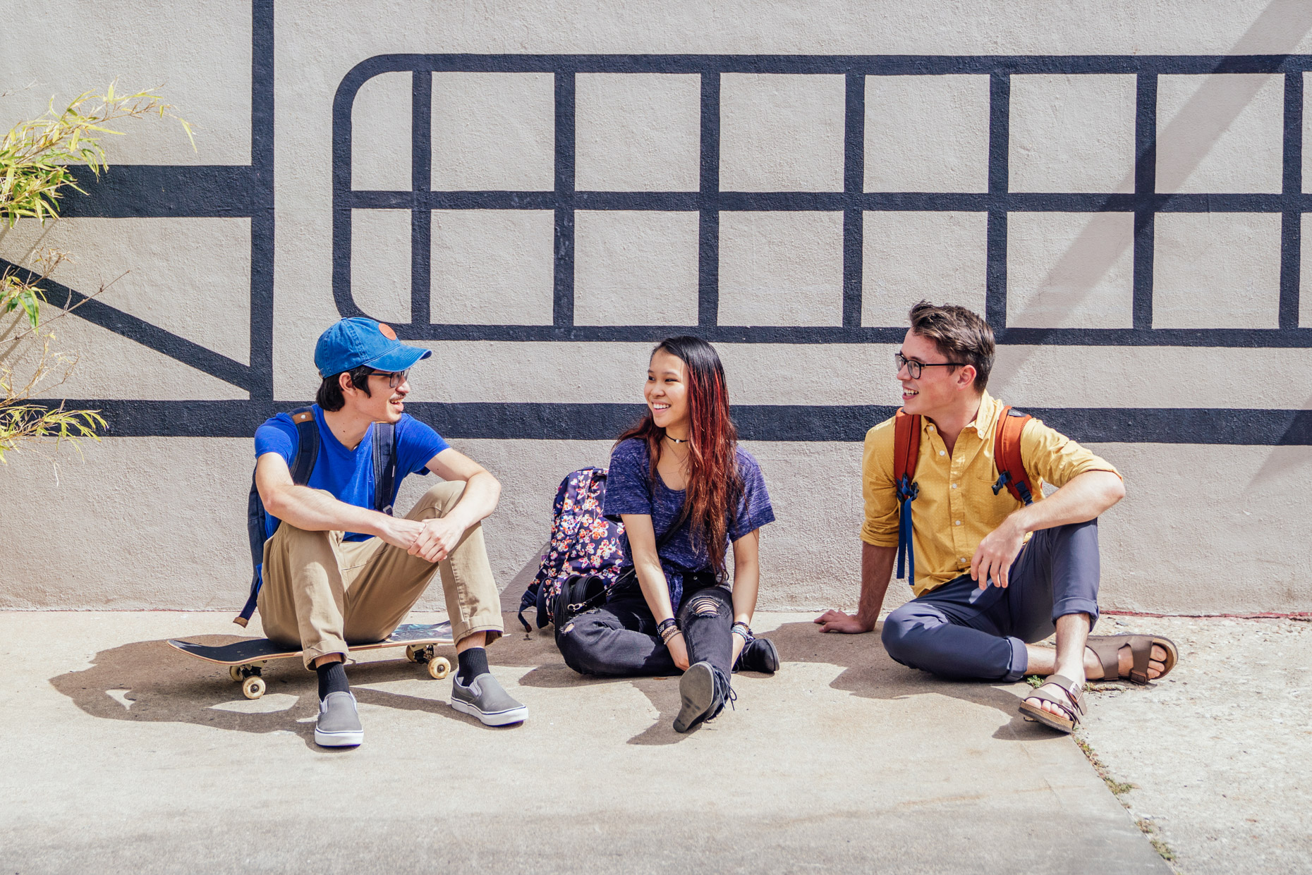 Happy Gen Z college students hanging out on side of building