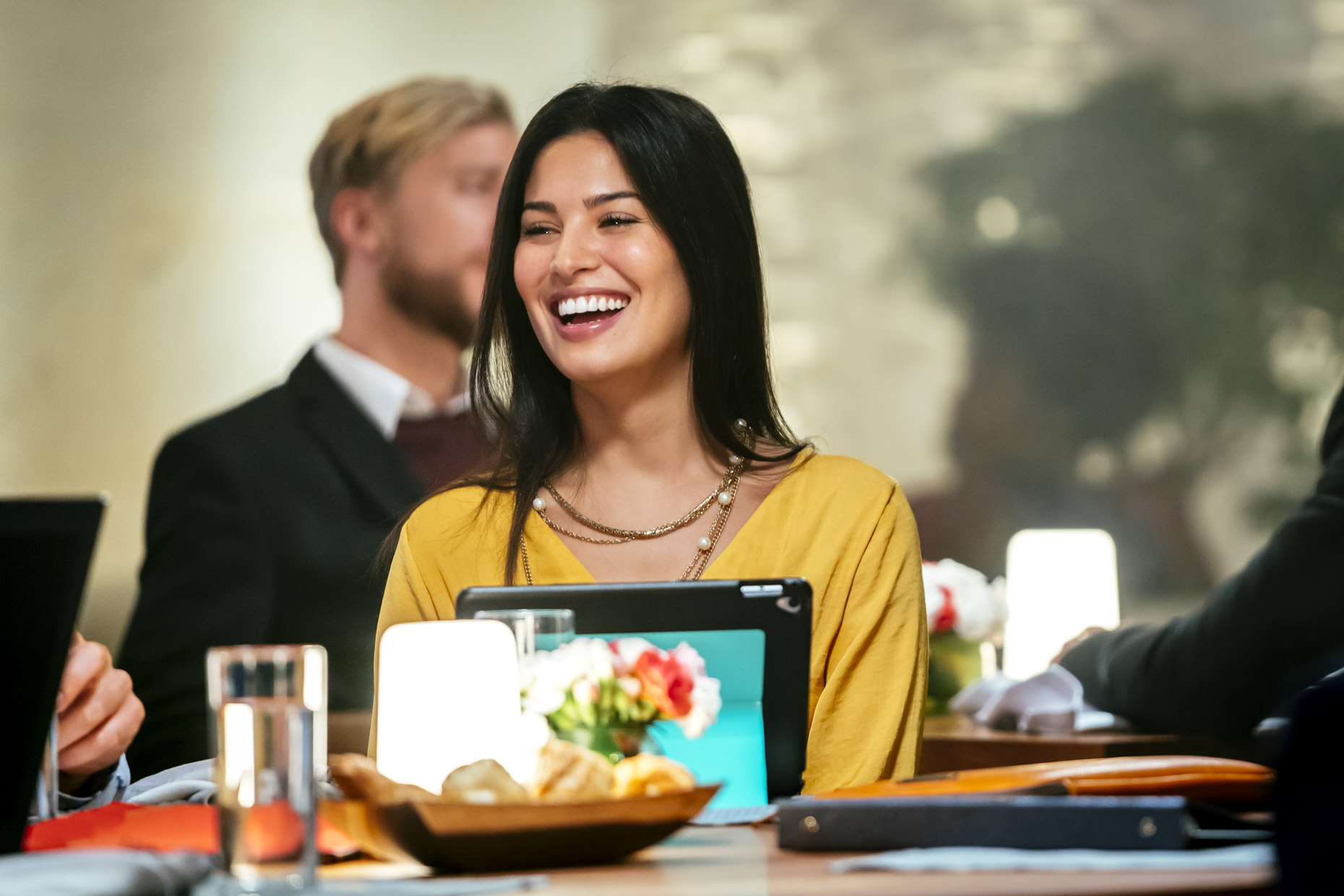 Happy woman at table in restaurant with ipad tablet computer