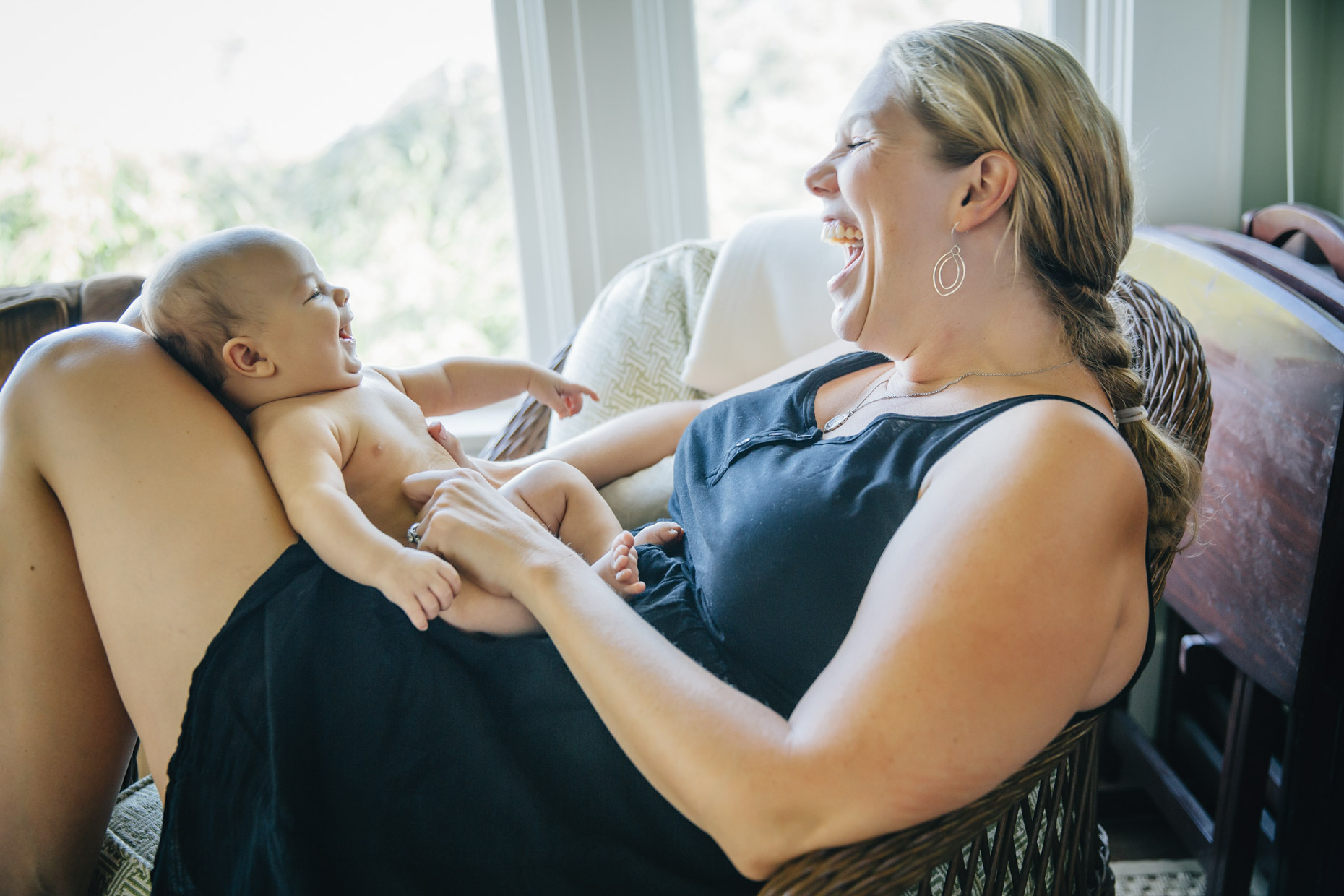 Happy woman playing with naked baby in her lap
