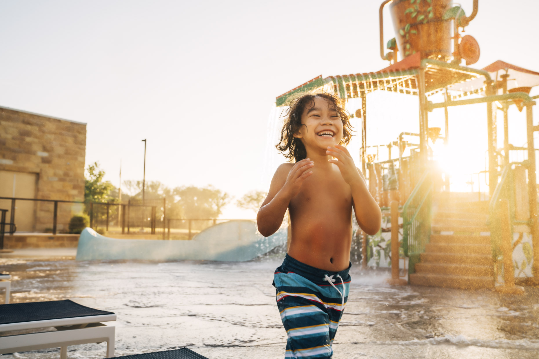 Hispanic boy playing in water park laughing