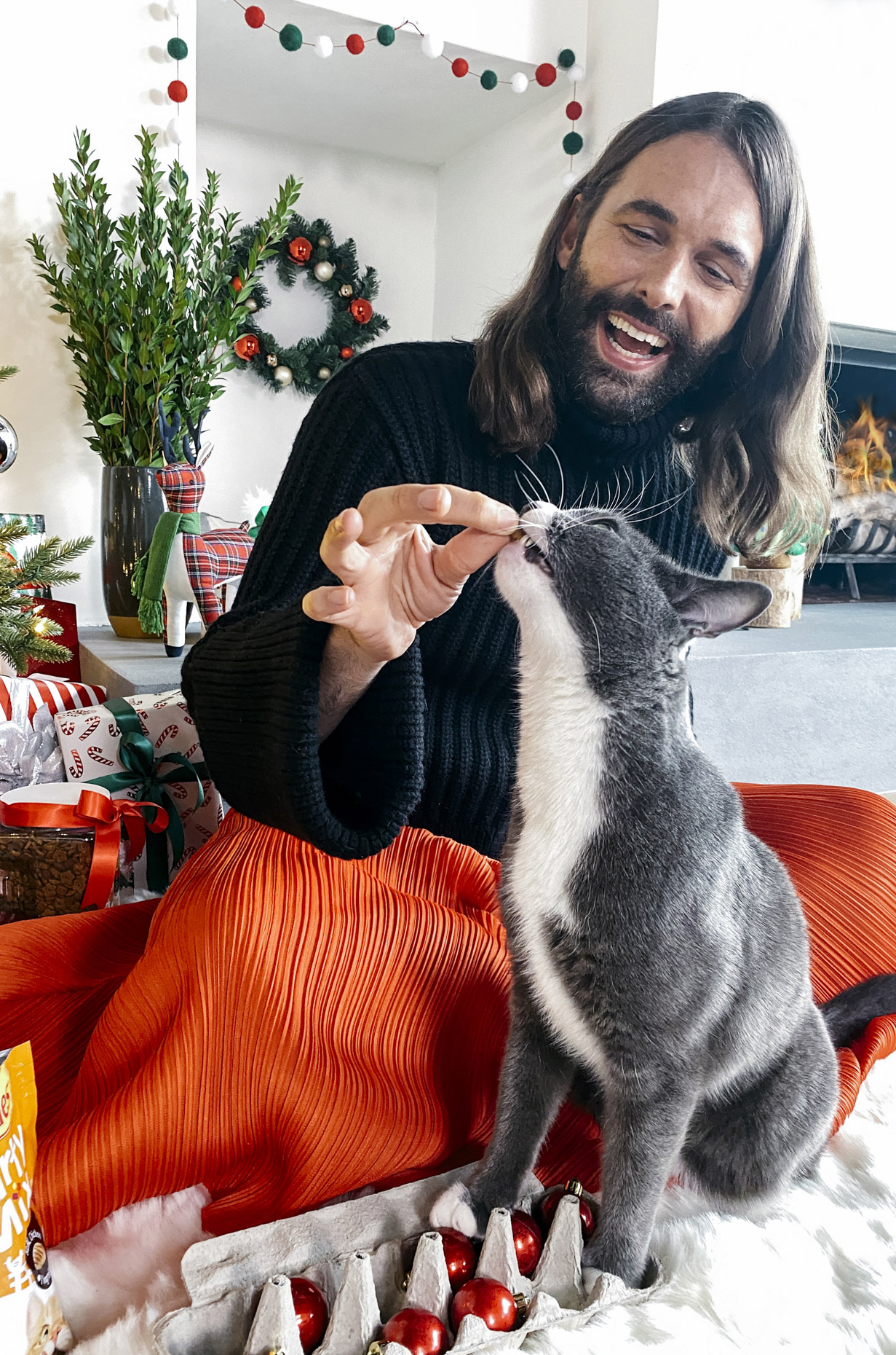 Jonathan Van Ness feeding cat Purina treat at Christmas