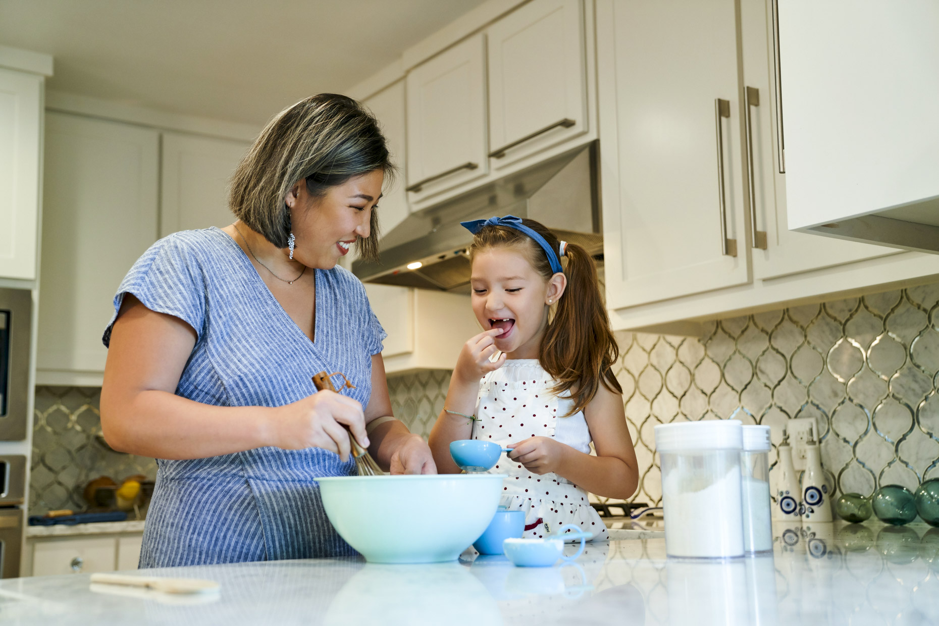 Korean girl baking cookies with her mom in home kitchen