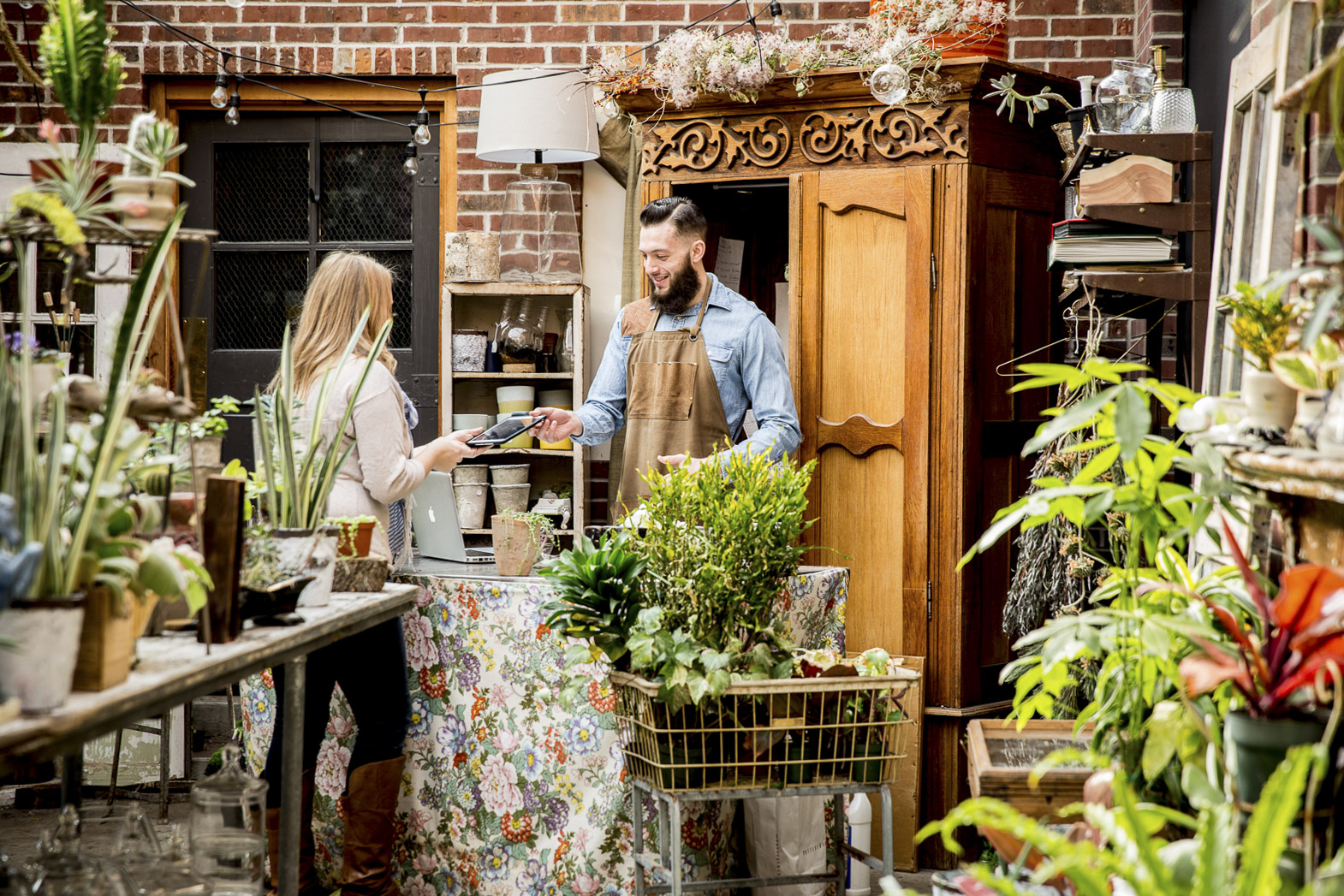 Man checking out customer in garden store on iPad tablet computer