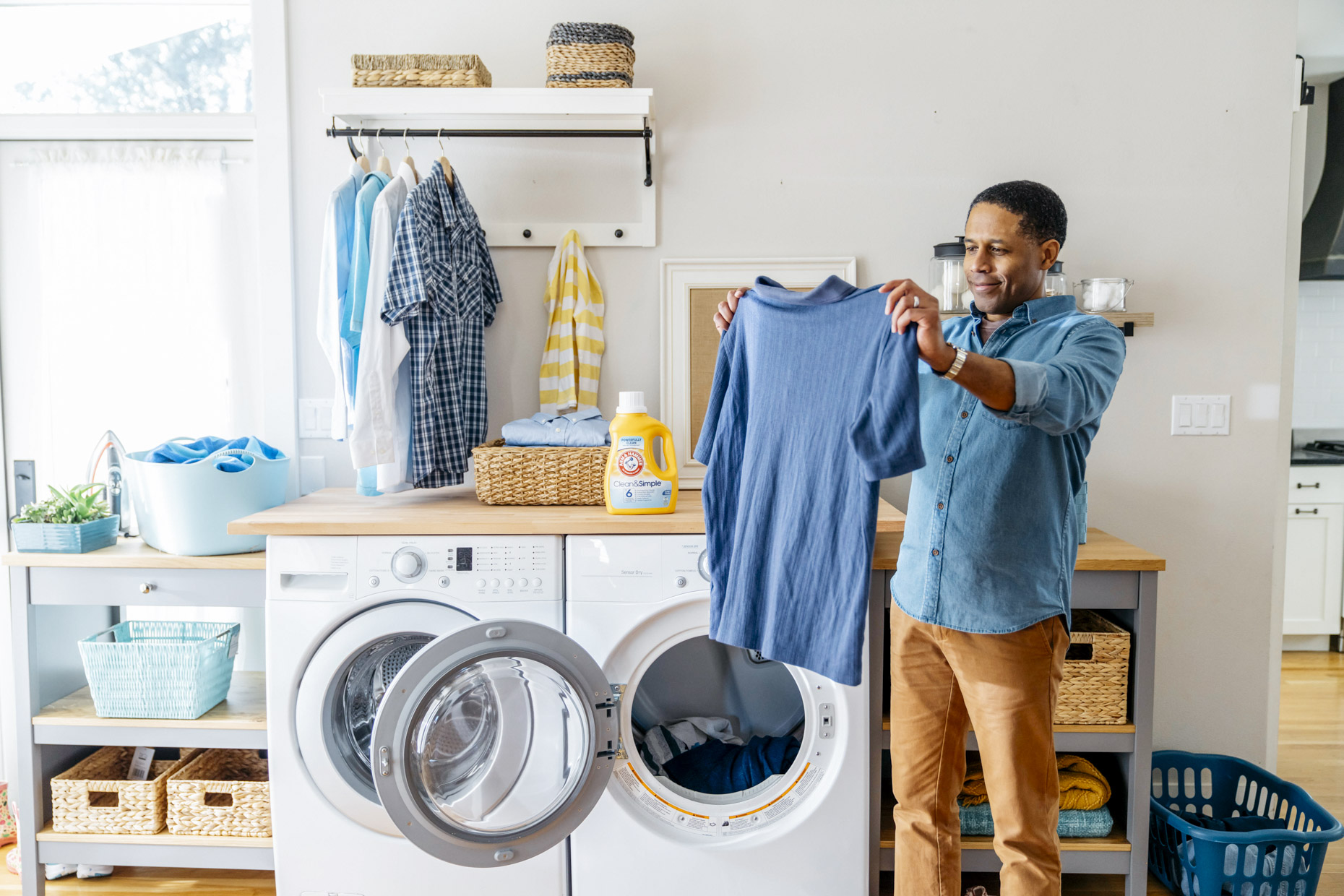 Man holding up freshly washed shirt in laundry room