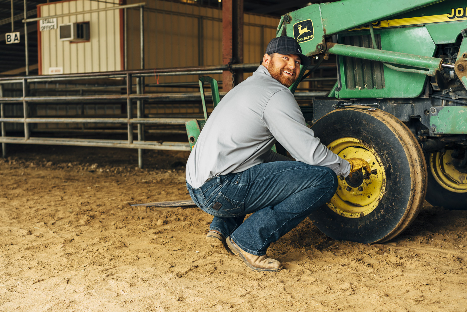 Man in wrangler jeans changing tire on john deere tractor
