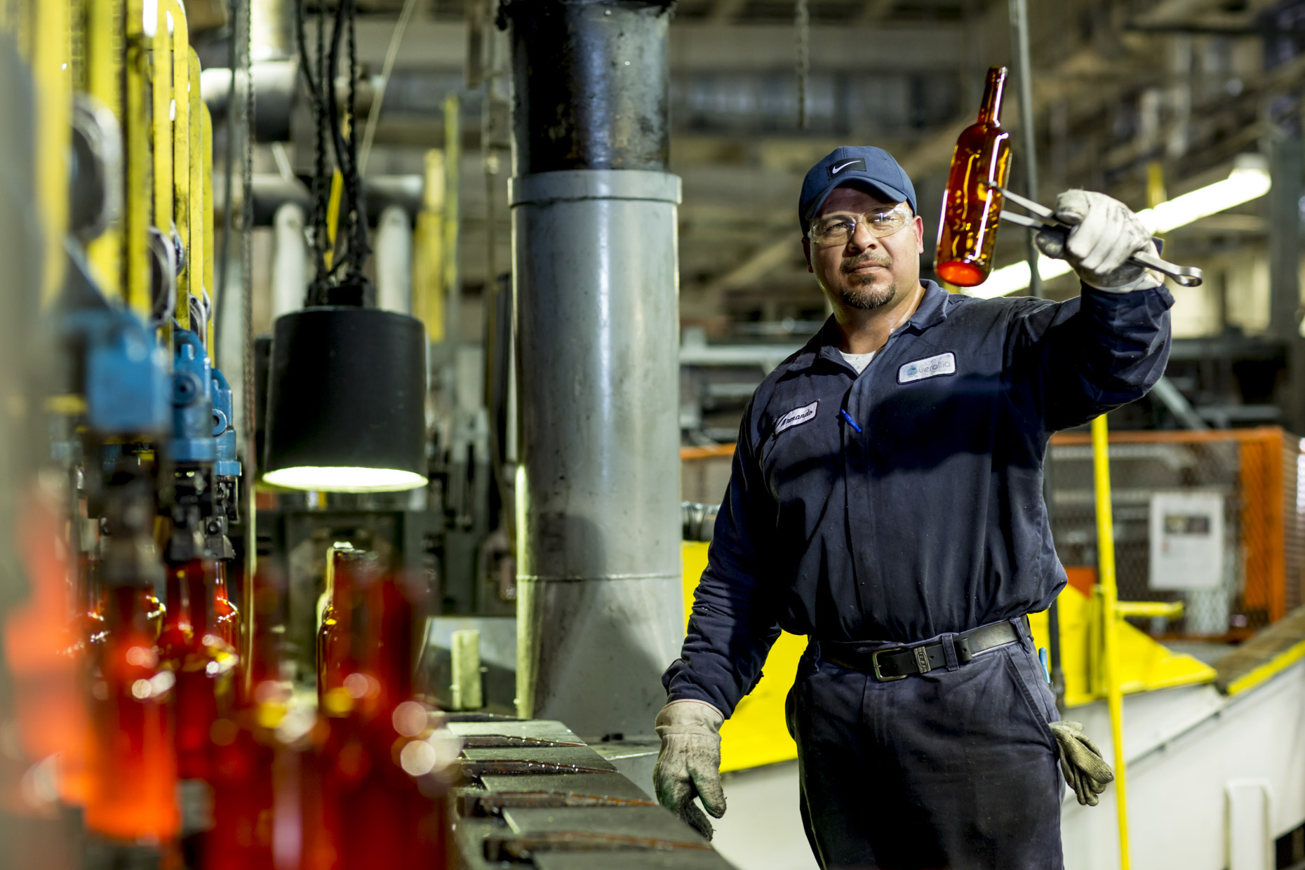 Man inspecting molton glass wine bottle in manufacturing factory
