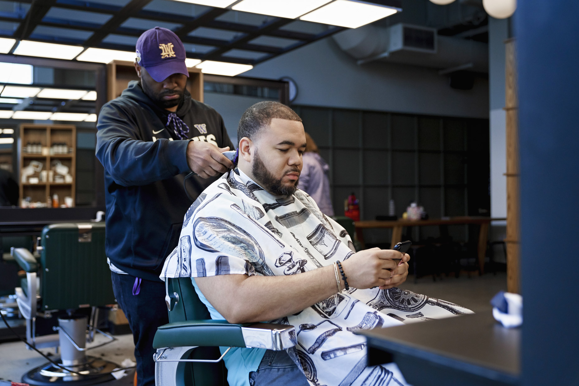 Man looking at phone while getting hair cut at barber shop