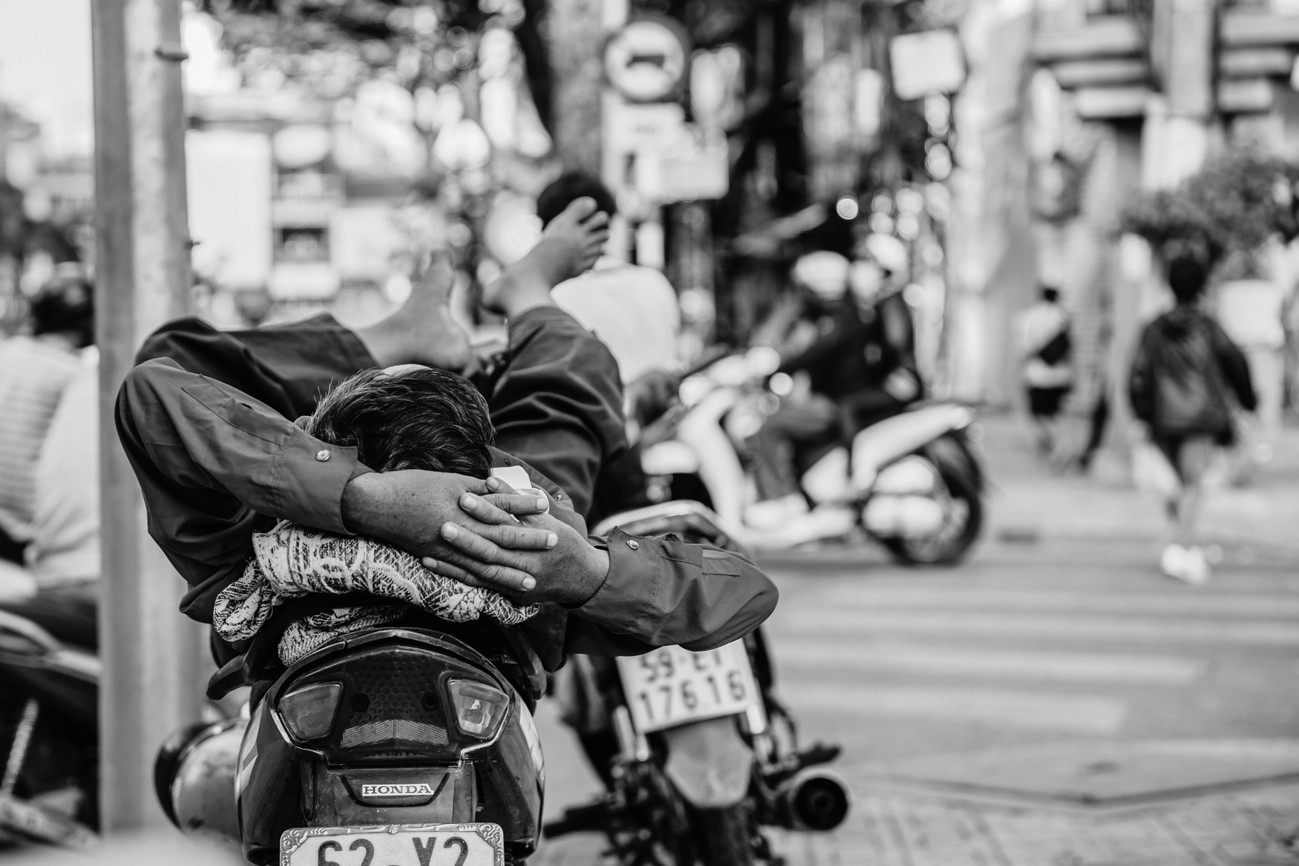 Man napping on motorcycle on busy street in Vietnam