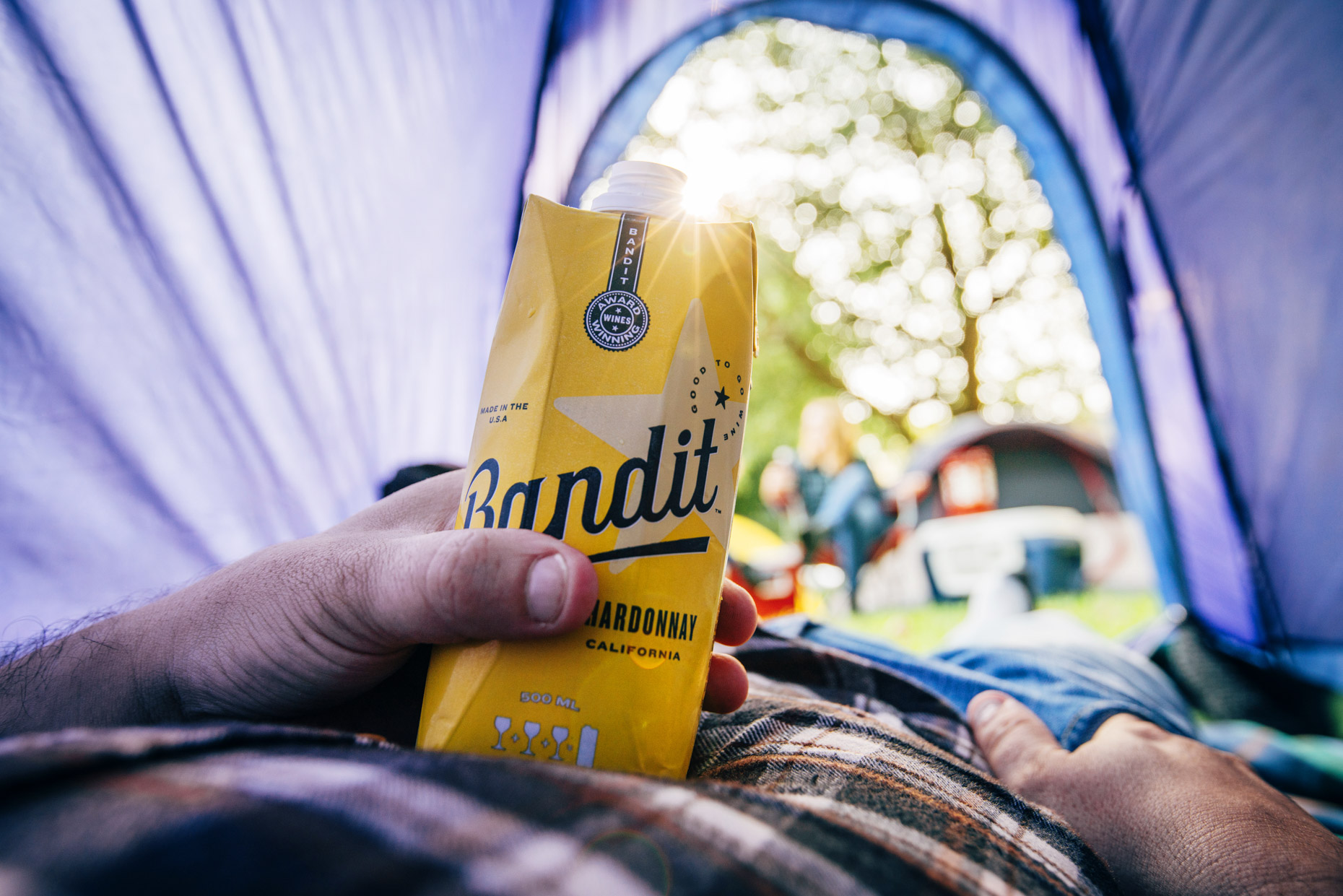 Man relaxing in tent with box of Bandit Chardonnay wine