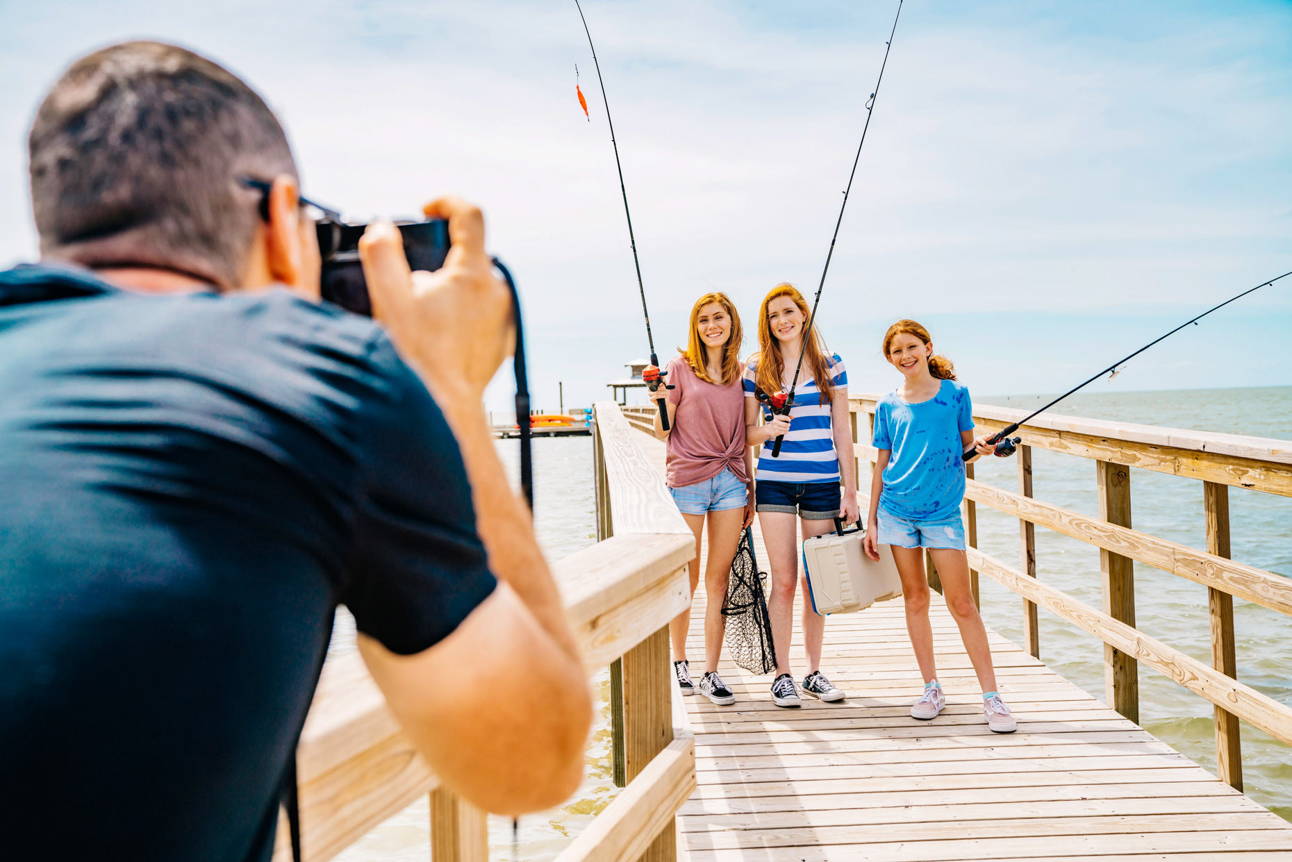 Man taking photo of girls on fishing dock