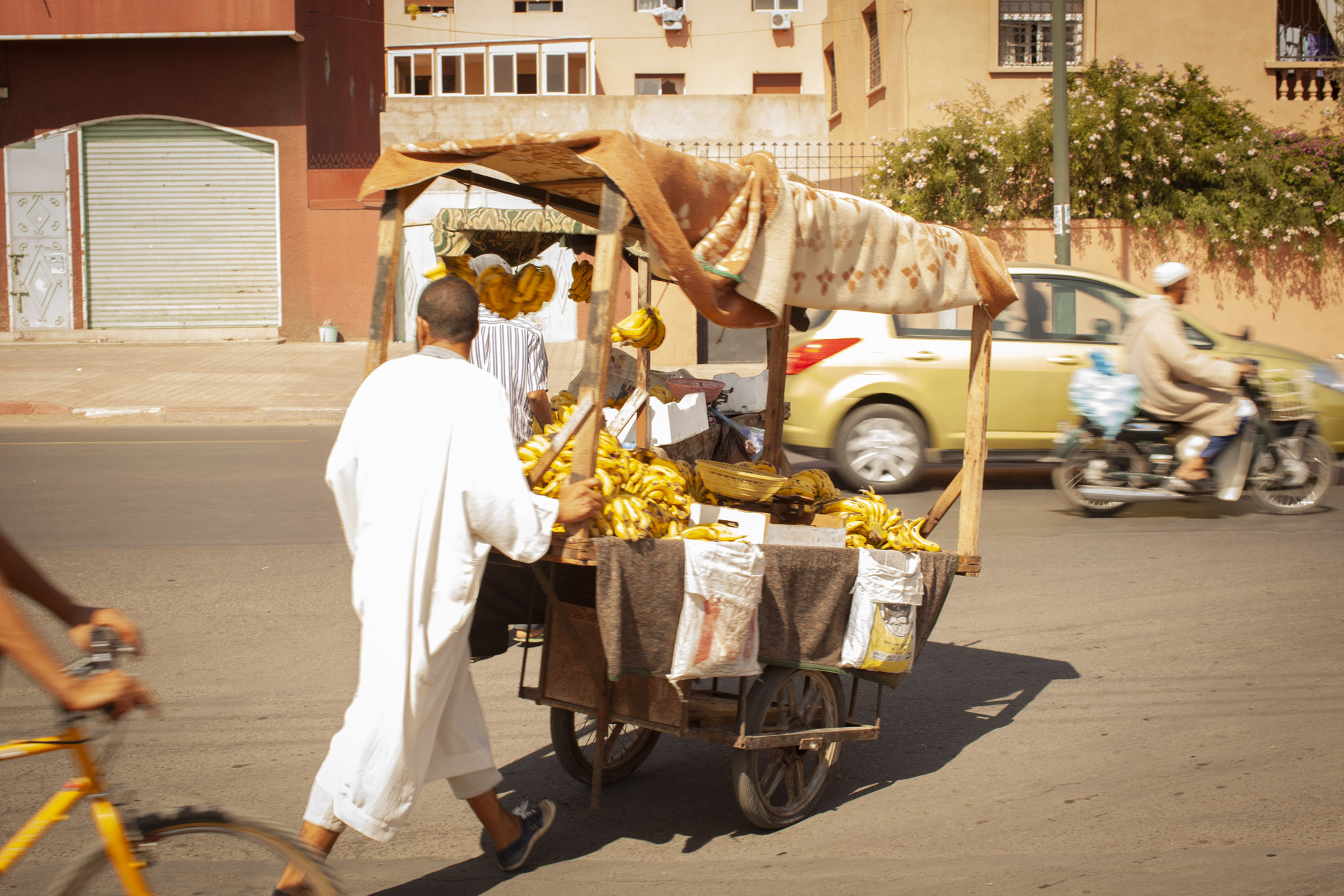 Man wheeling cart of bananas down the street in Marrakesh, Morocco
