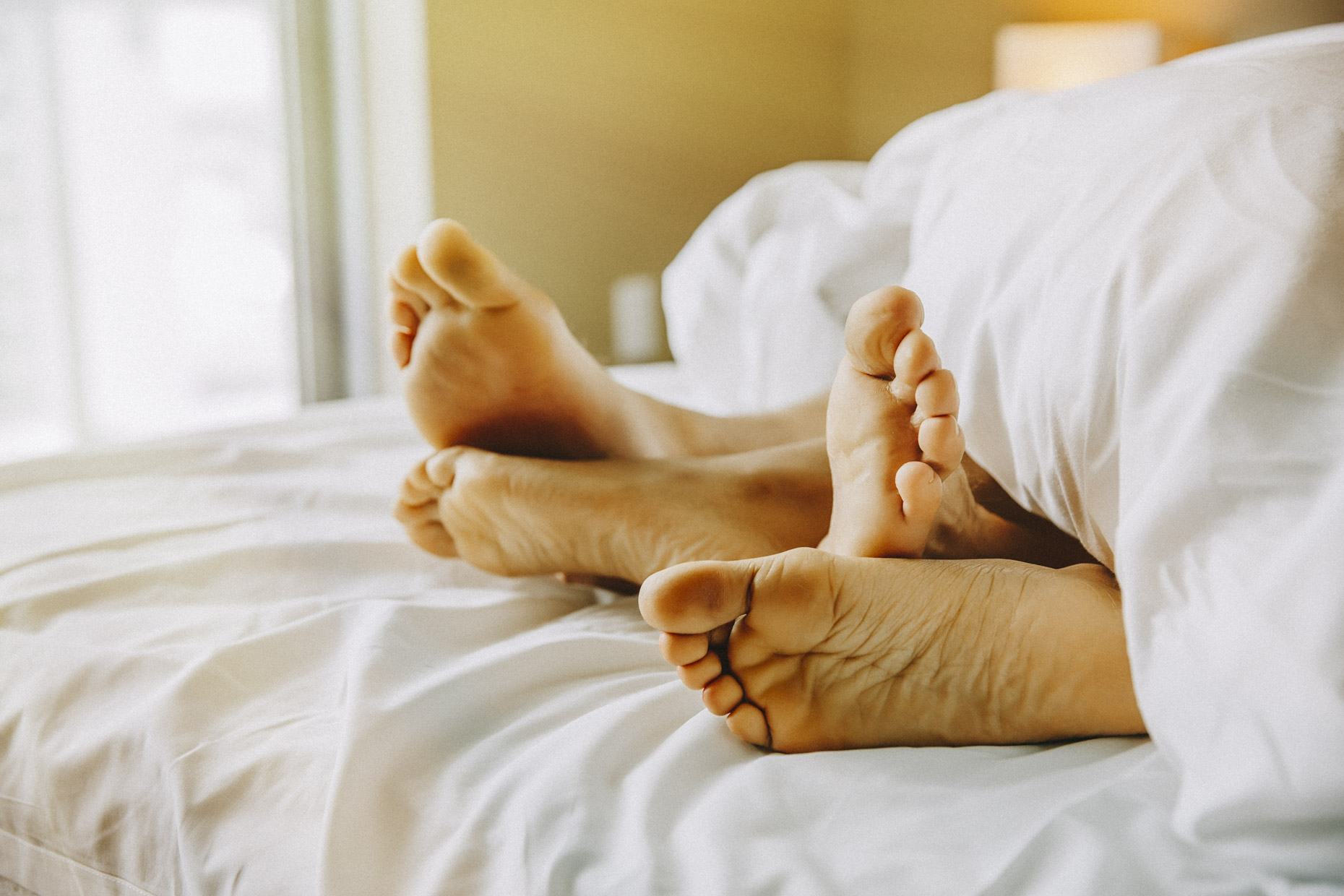 Man-woman-feet-on-bed-hotel-resort-l-Inti-St-Clair-is201504251590