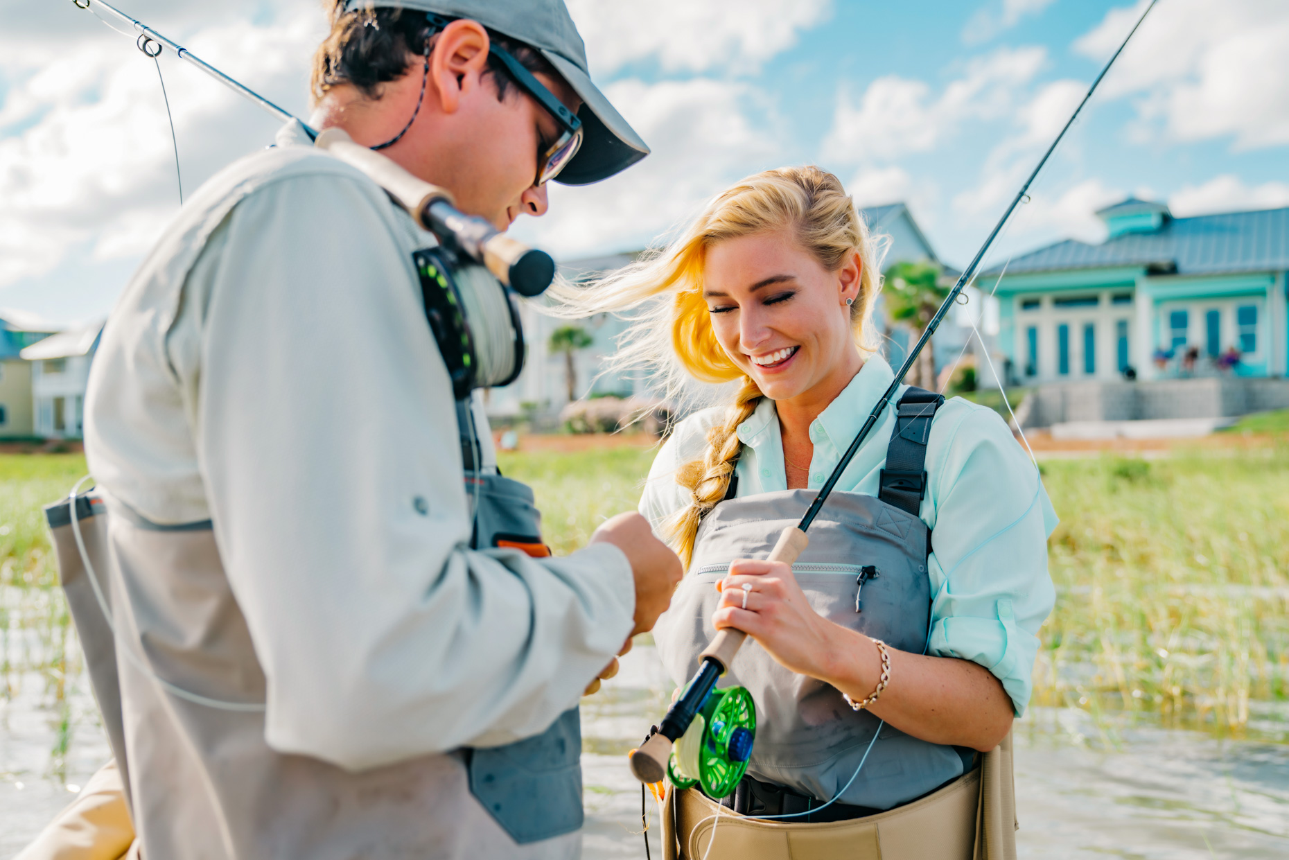 Man helping smiling woman bait fly fishing hook