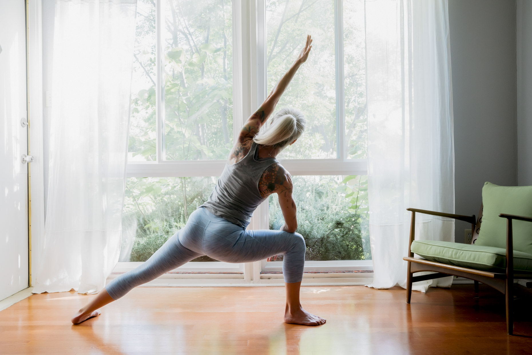 Mature woman with long grey hair practicing yoga at home