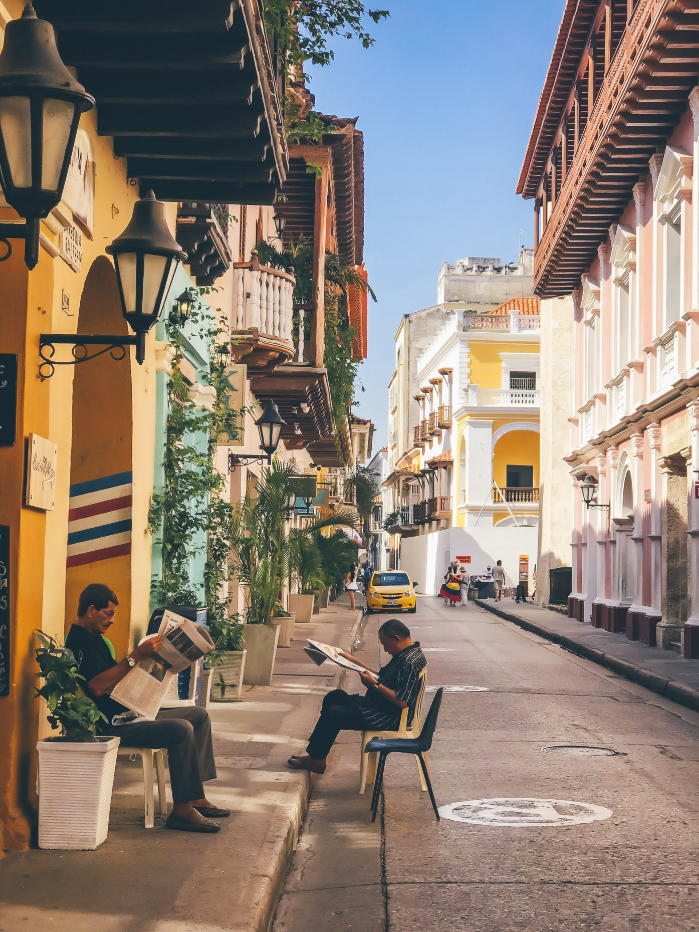 Old men sitting on sidewalk in Cartagena Colombia reading newspapers