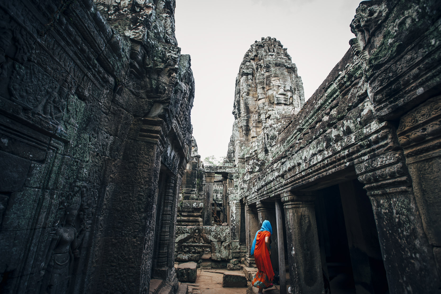 Muslim woman in orange dress and blue head scarf exploring the ruins of Angkor Wat