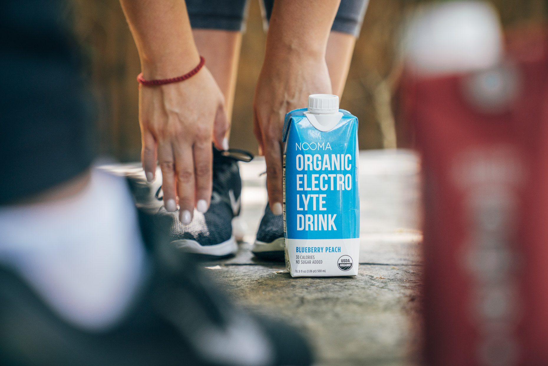 Woman stretching touching toes next to Nooma electrolyte drink