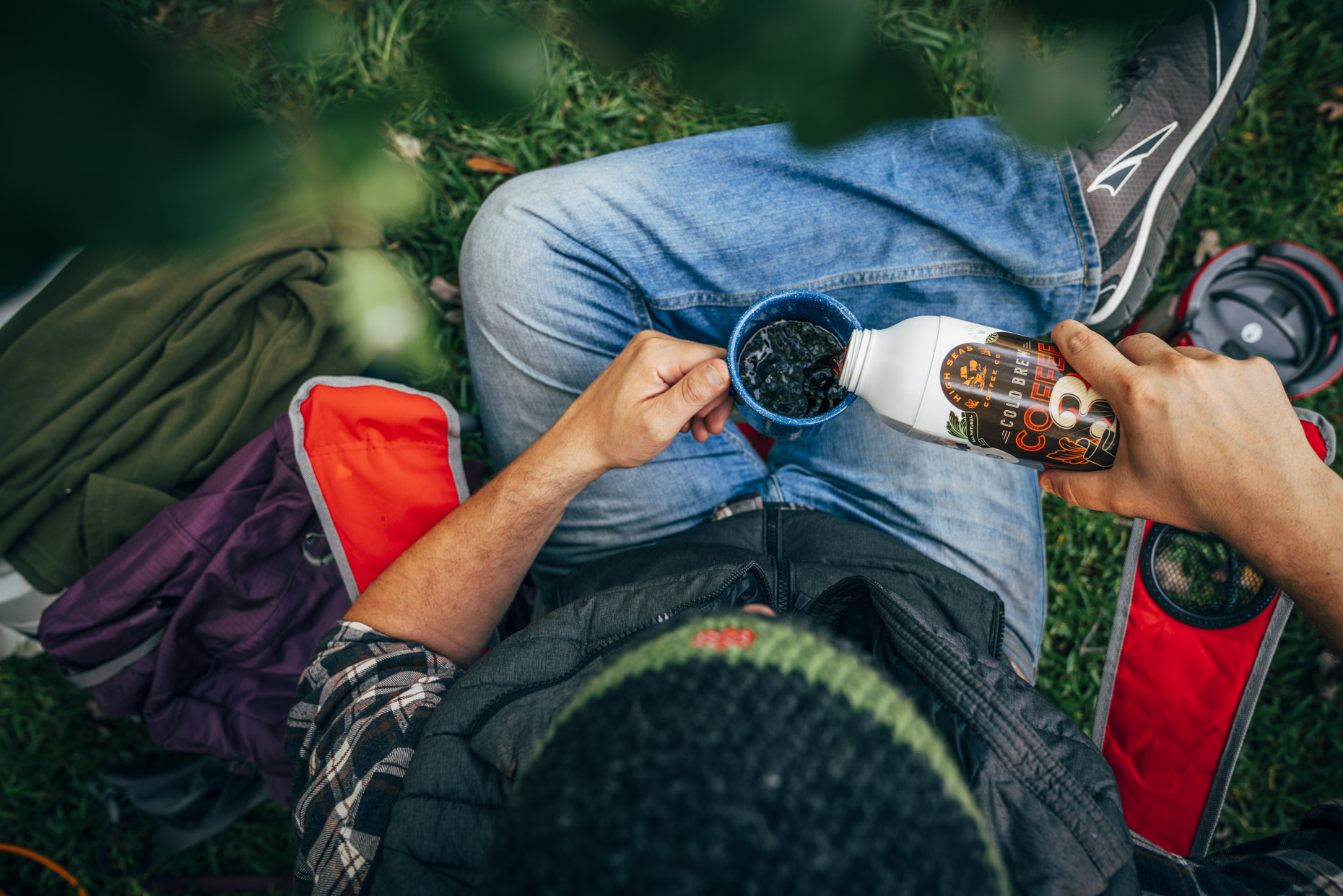 Overhead view of man pouring coffee into mug while camping