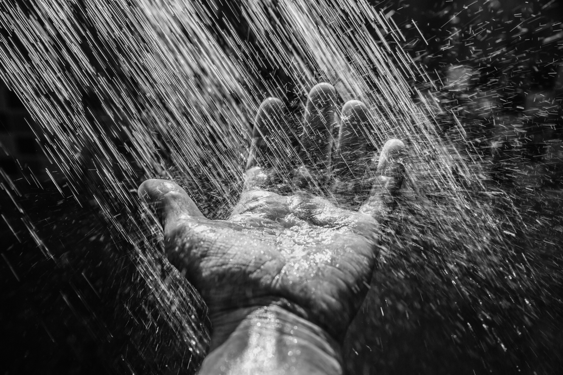 POV of outstretched hand in rain in black and white