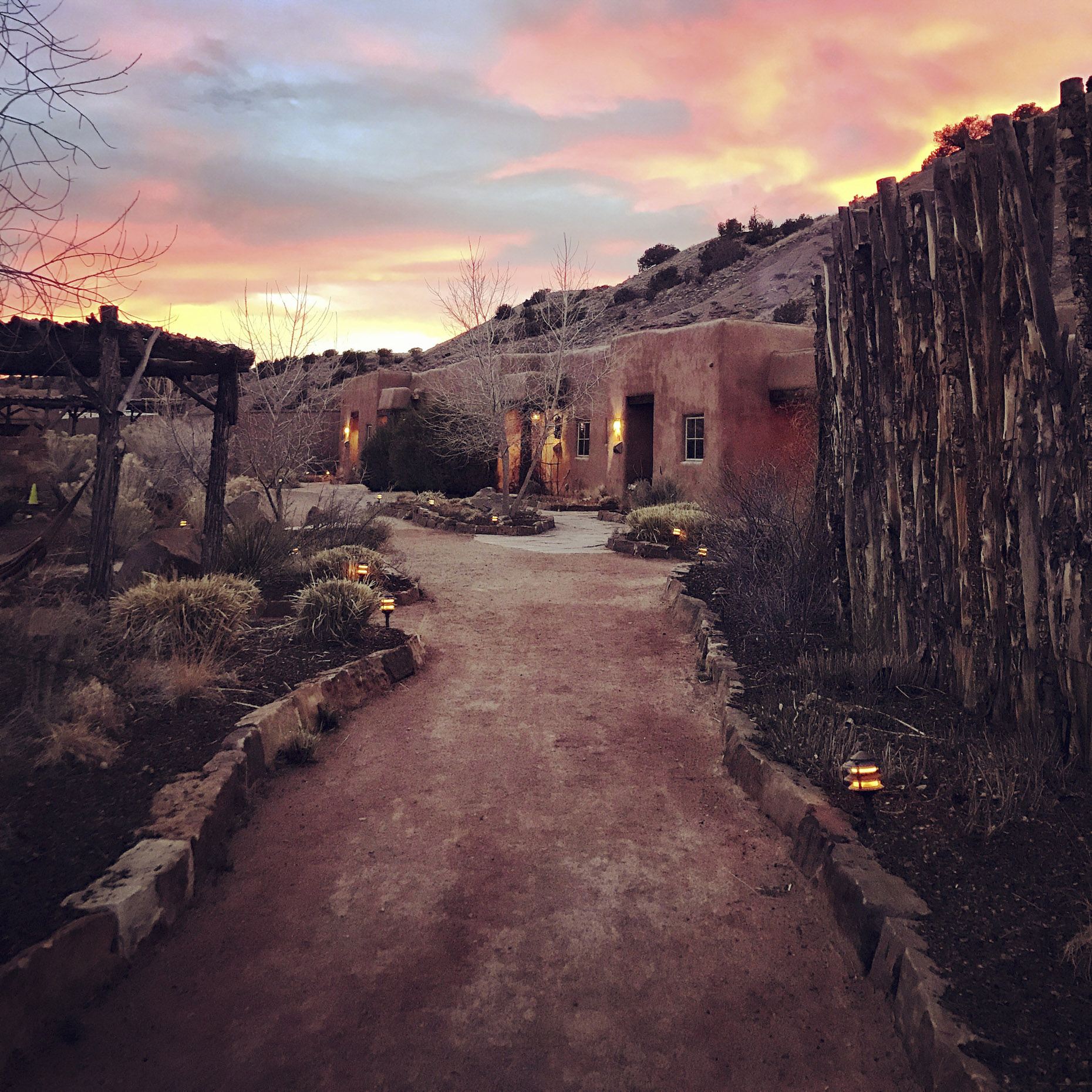 Pathway to adobe building lit up at sunset