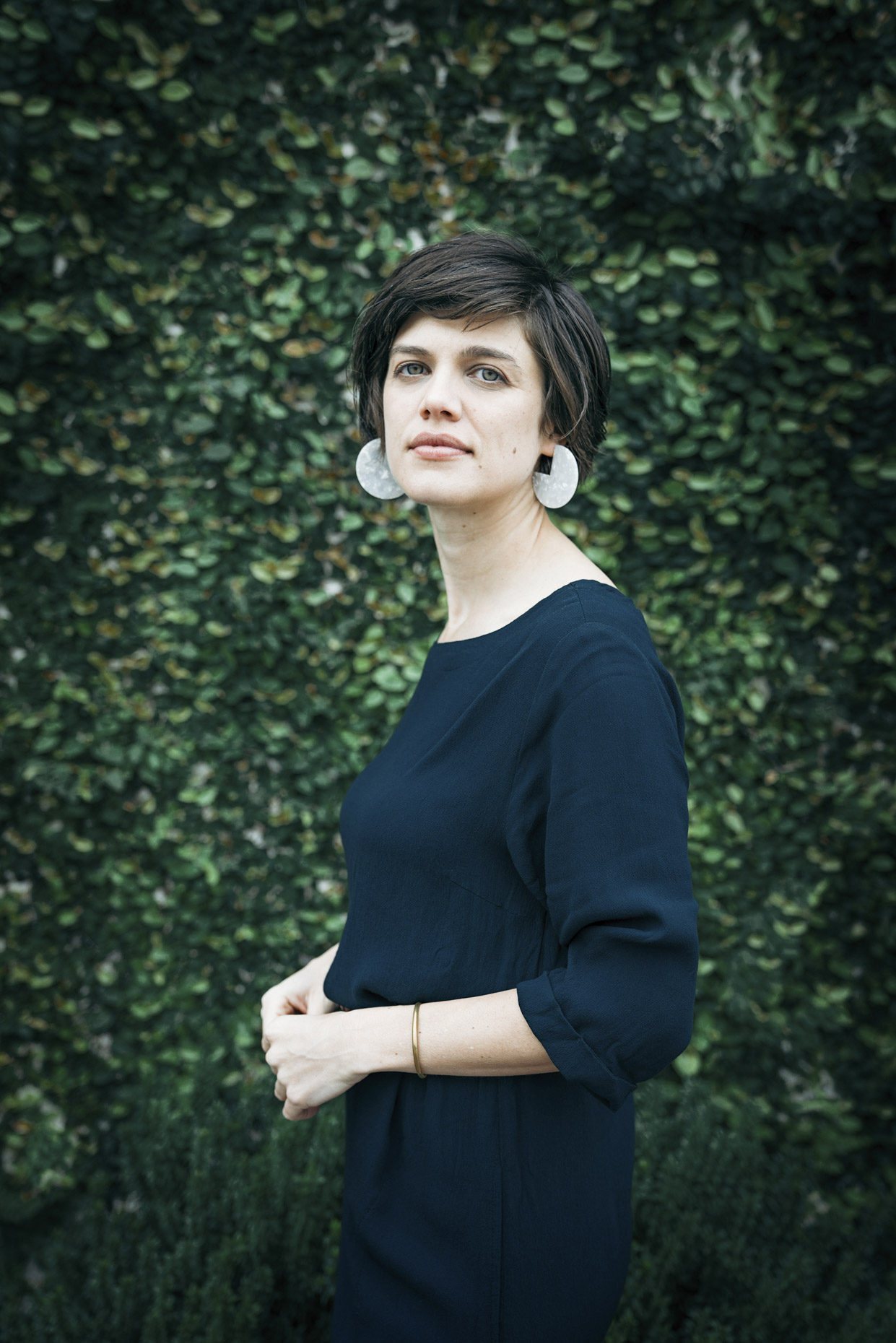 Portrait of professional coach Laurn Russo in front of green plant wall