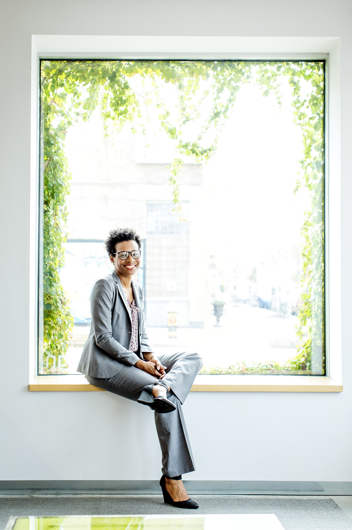Portrait of black business woman in suit sitting in office window