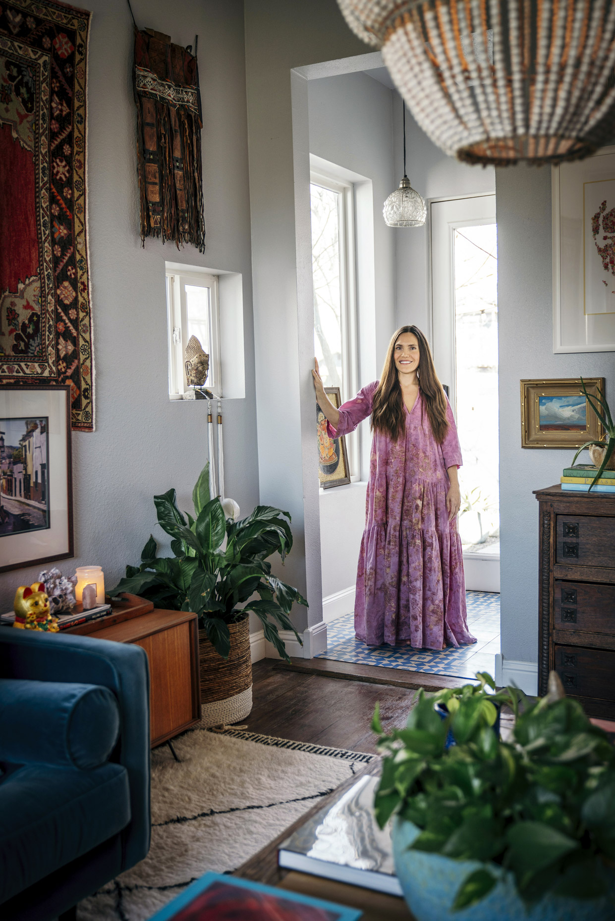 Portrait of woman in long pink dress in art-filled home