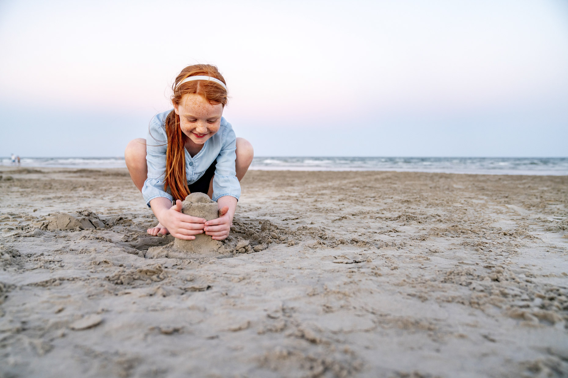 Red haired girl building sand castle